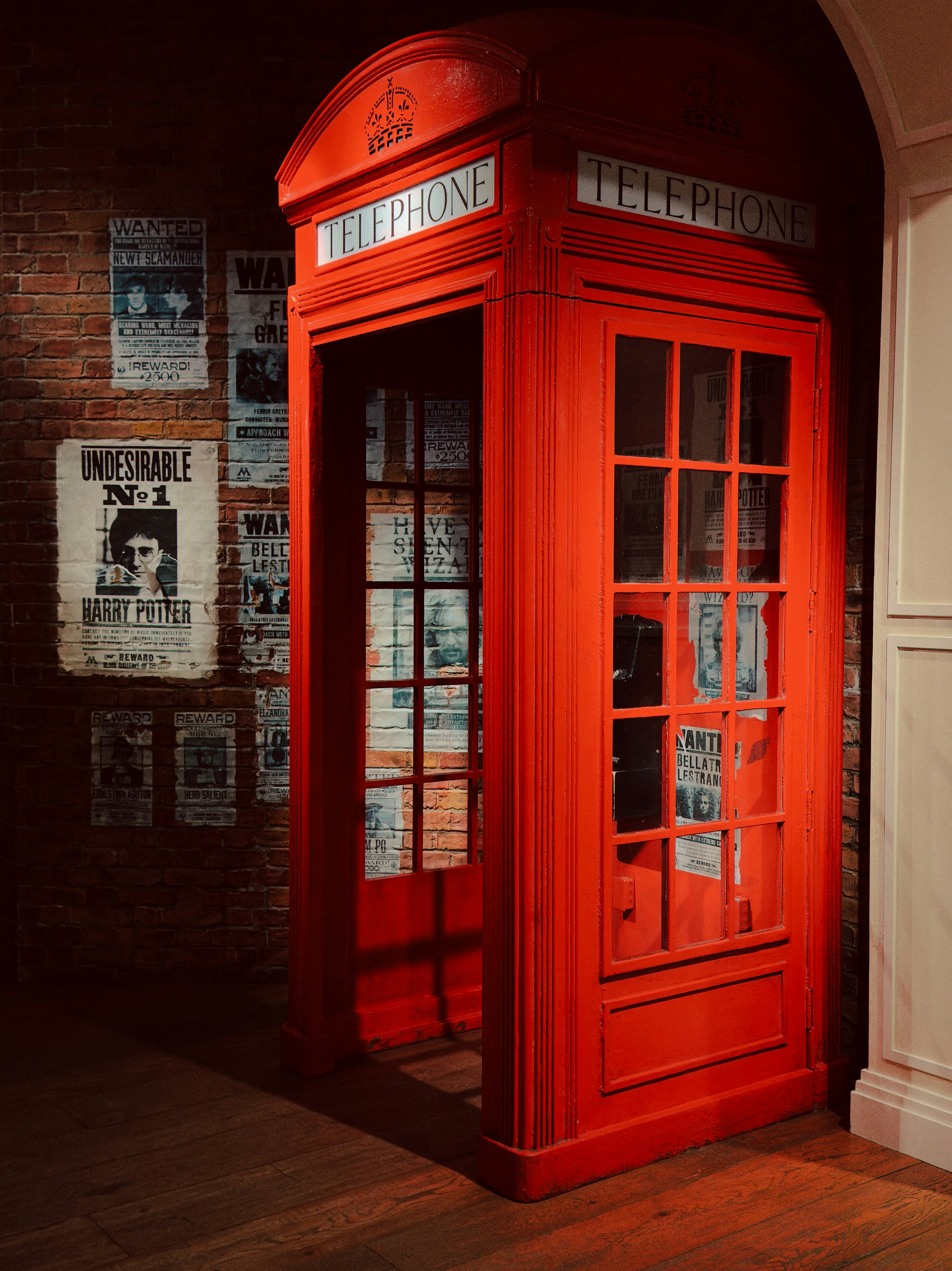 A vintage red british telephone booth with posters on wall.