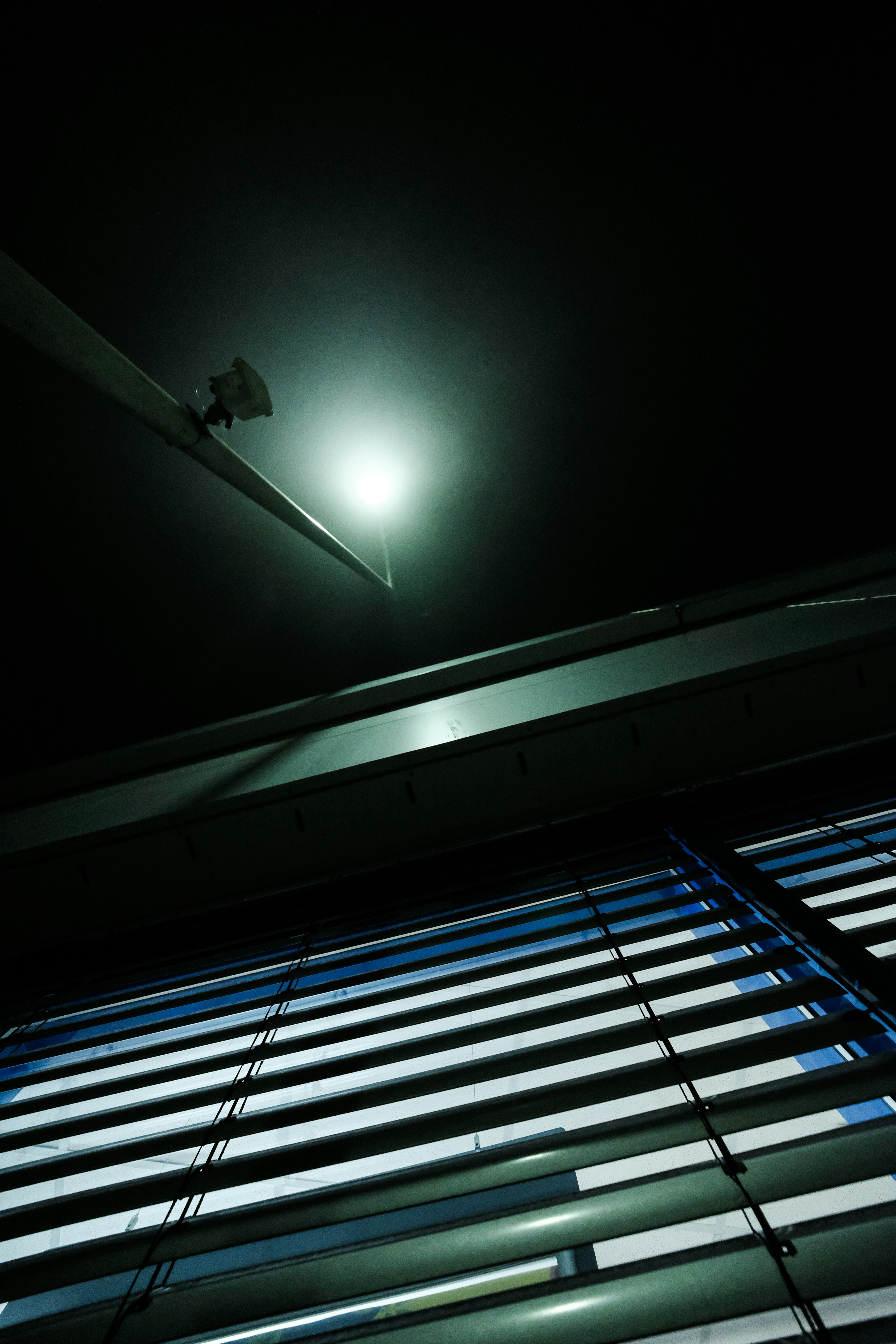 Straßenlaterne beleuchtet Jalousien gegen den dunklen Himmel.