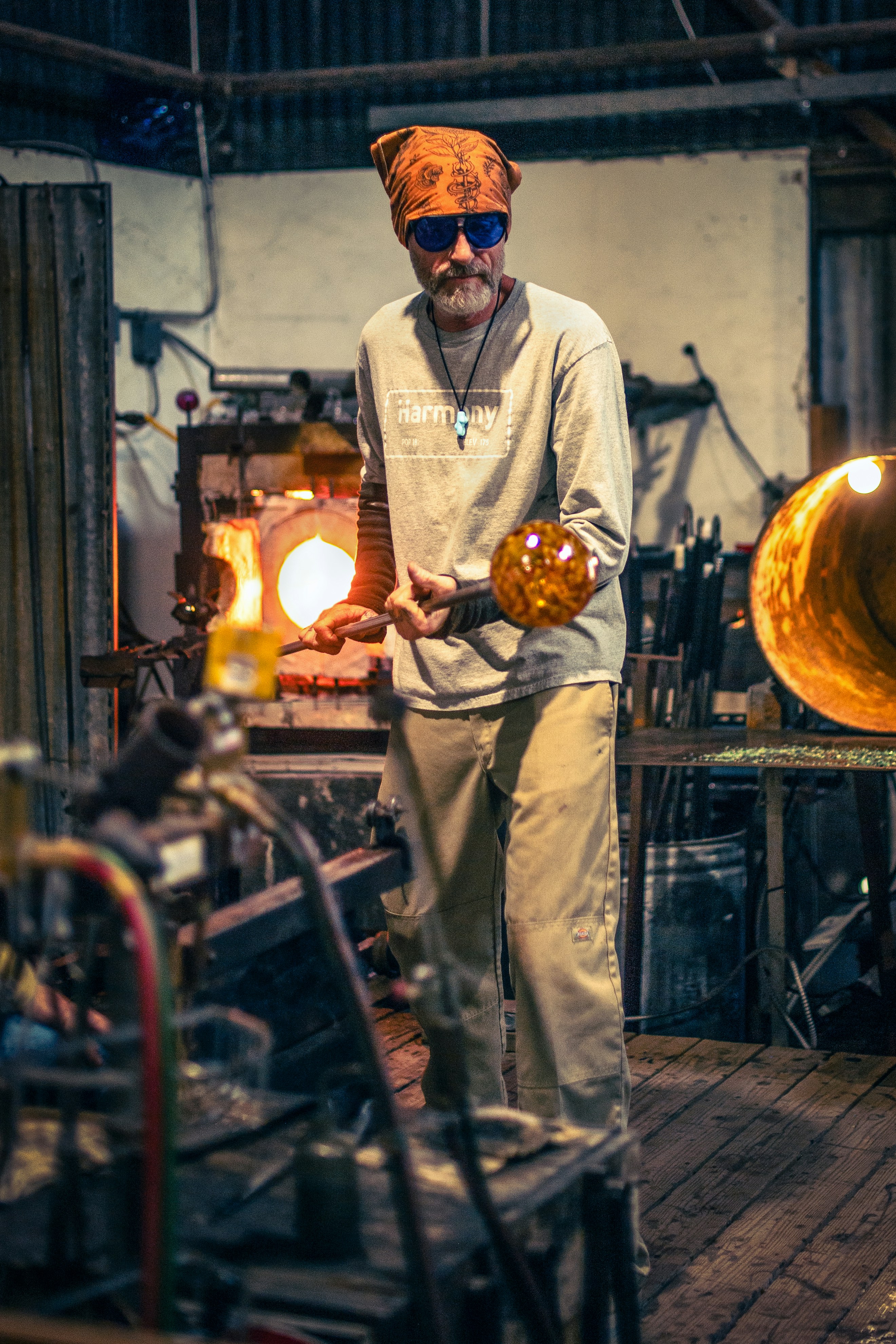 Glassblower holds molten glass in workshop