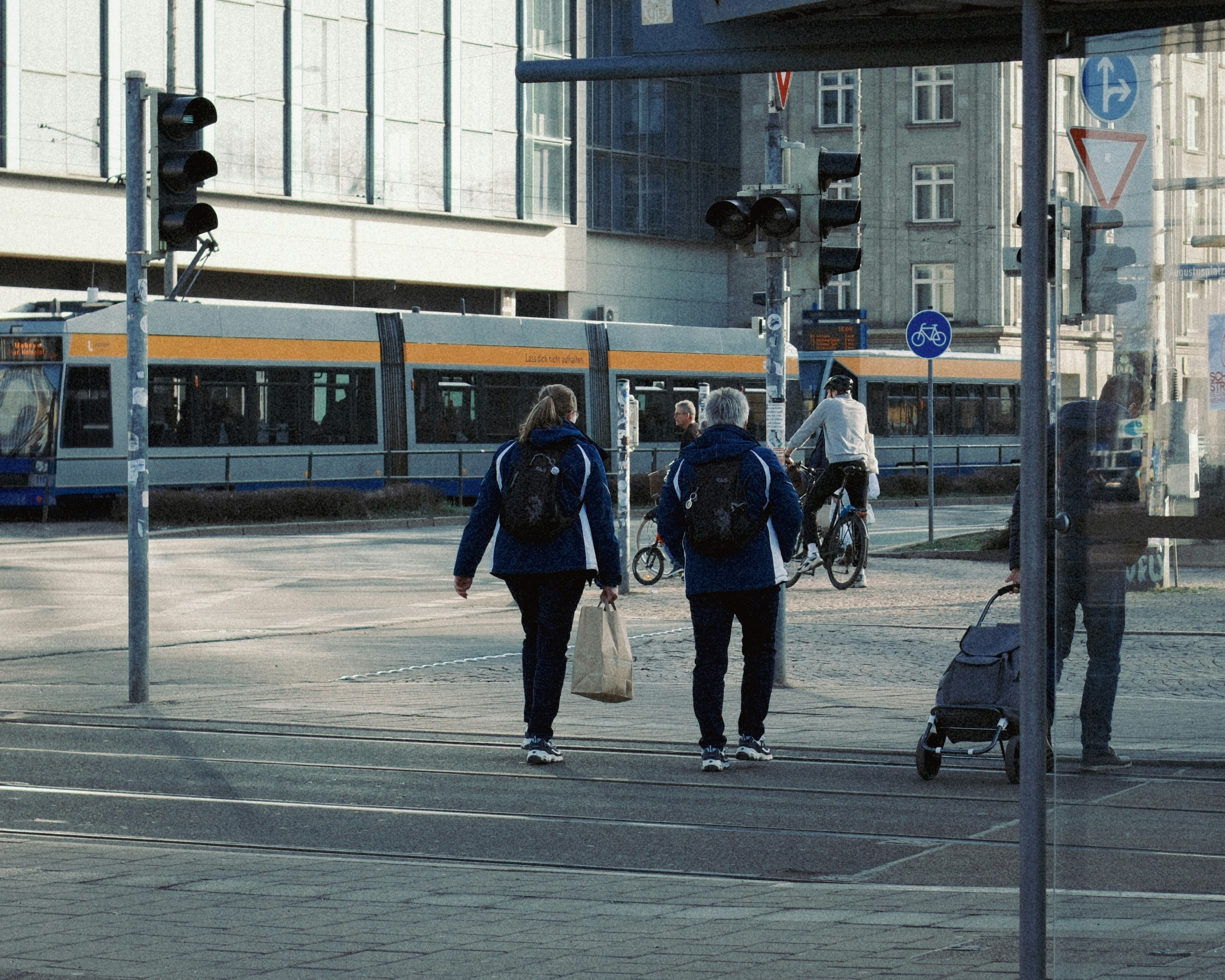 Menschen überqueren die Straße mit Straßenbahn im Hintergrund