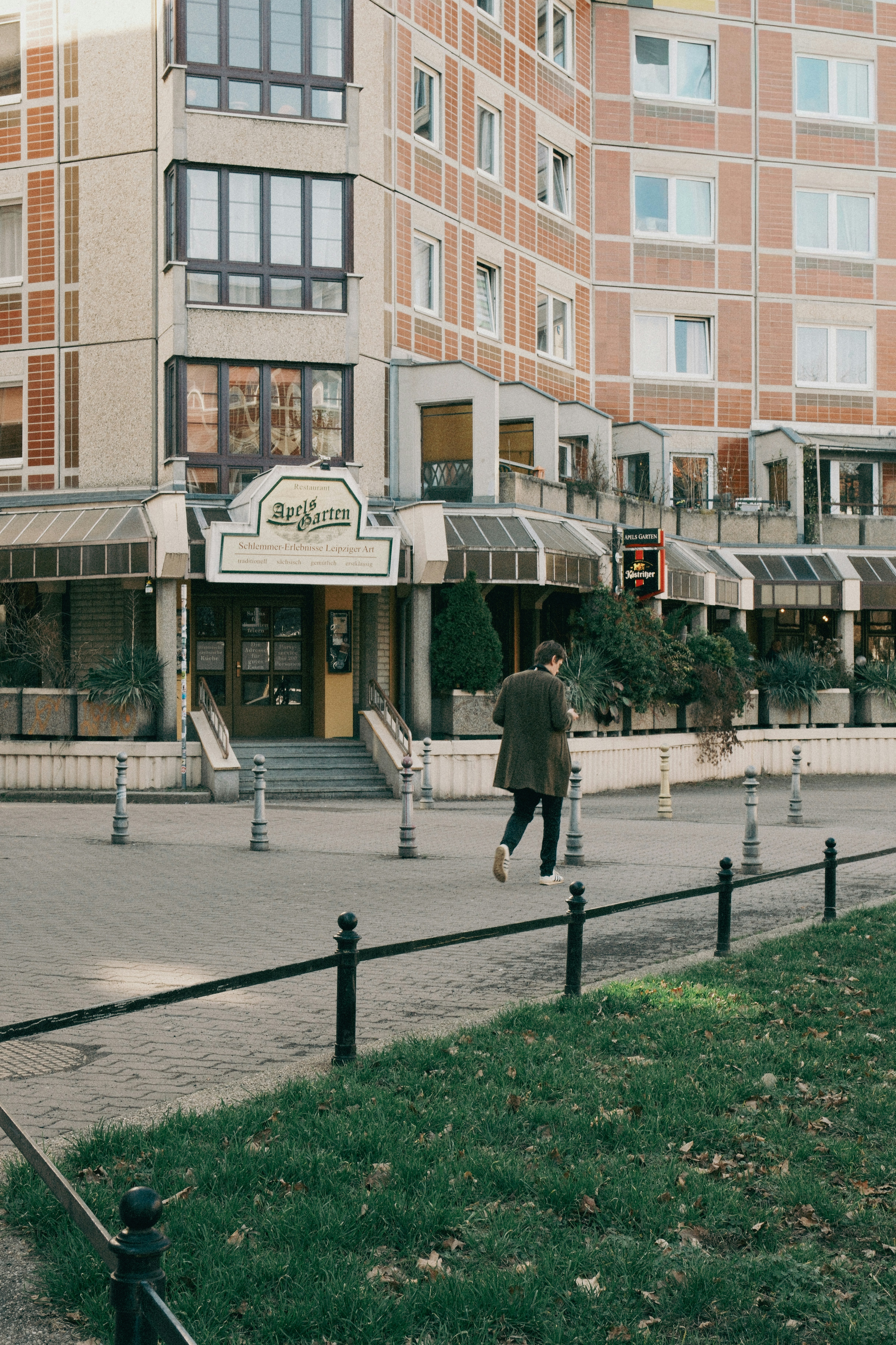 Person, die an Wohnhäusern und Geschäften vorbeigeht.