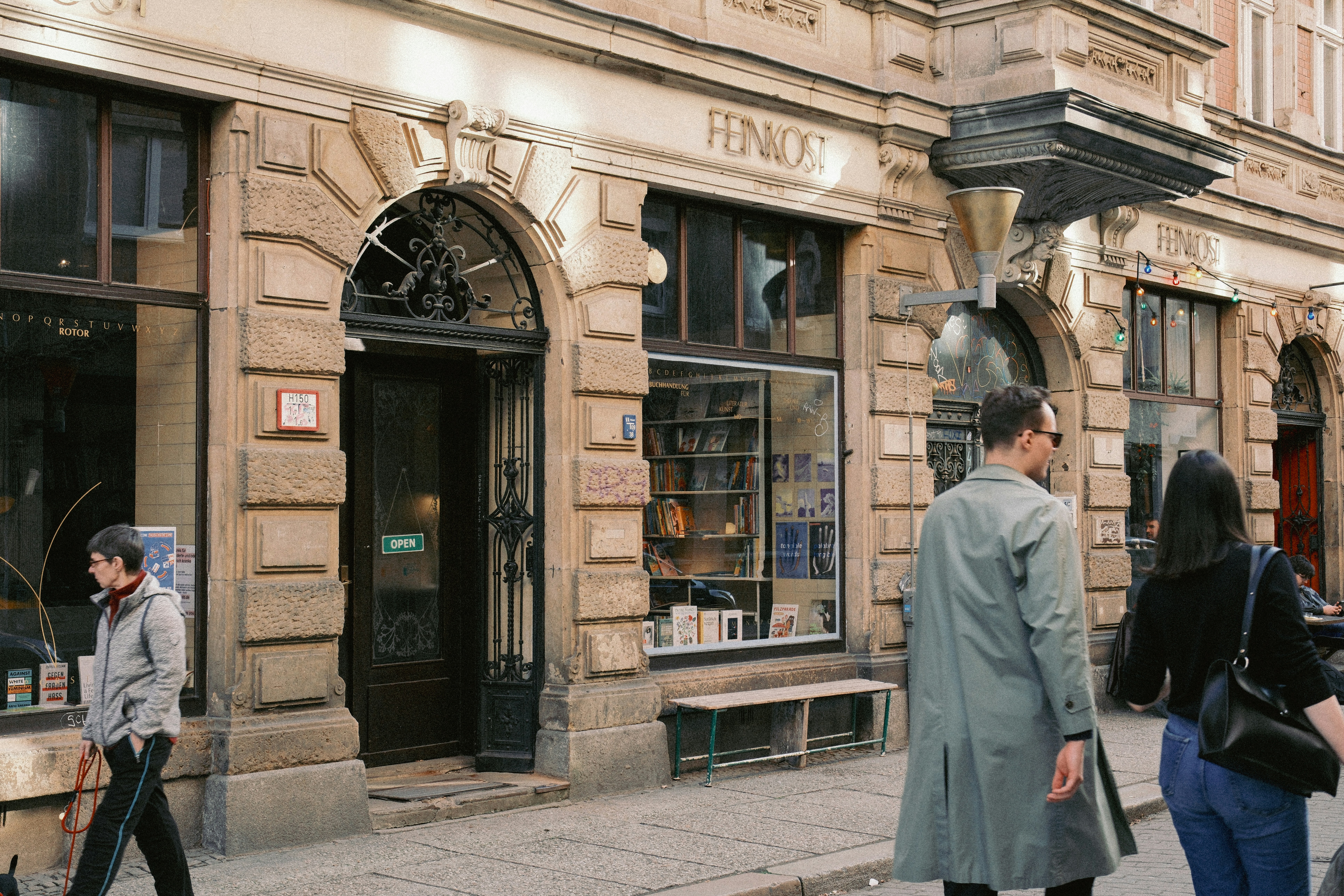 Die Leute gehen an einem Geschäft mit steinerner Fassade vorbei.