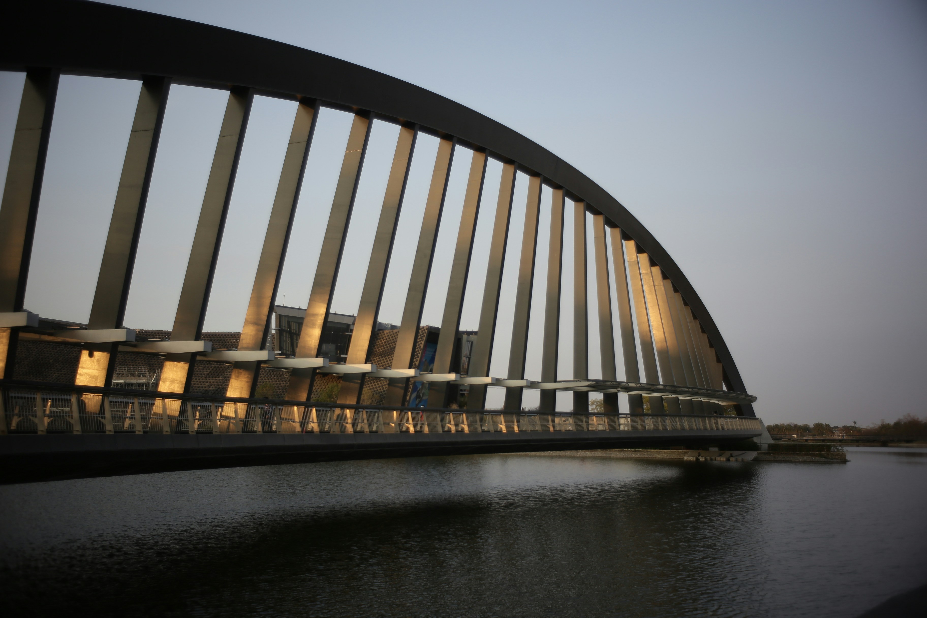 Arco moderno de ponte sobre águas calmas ao entardecer