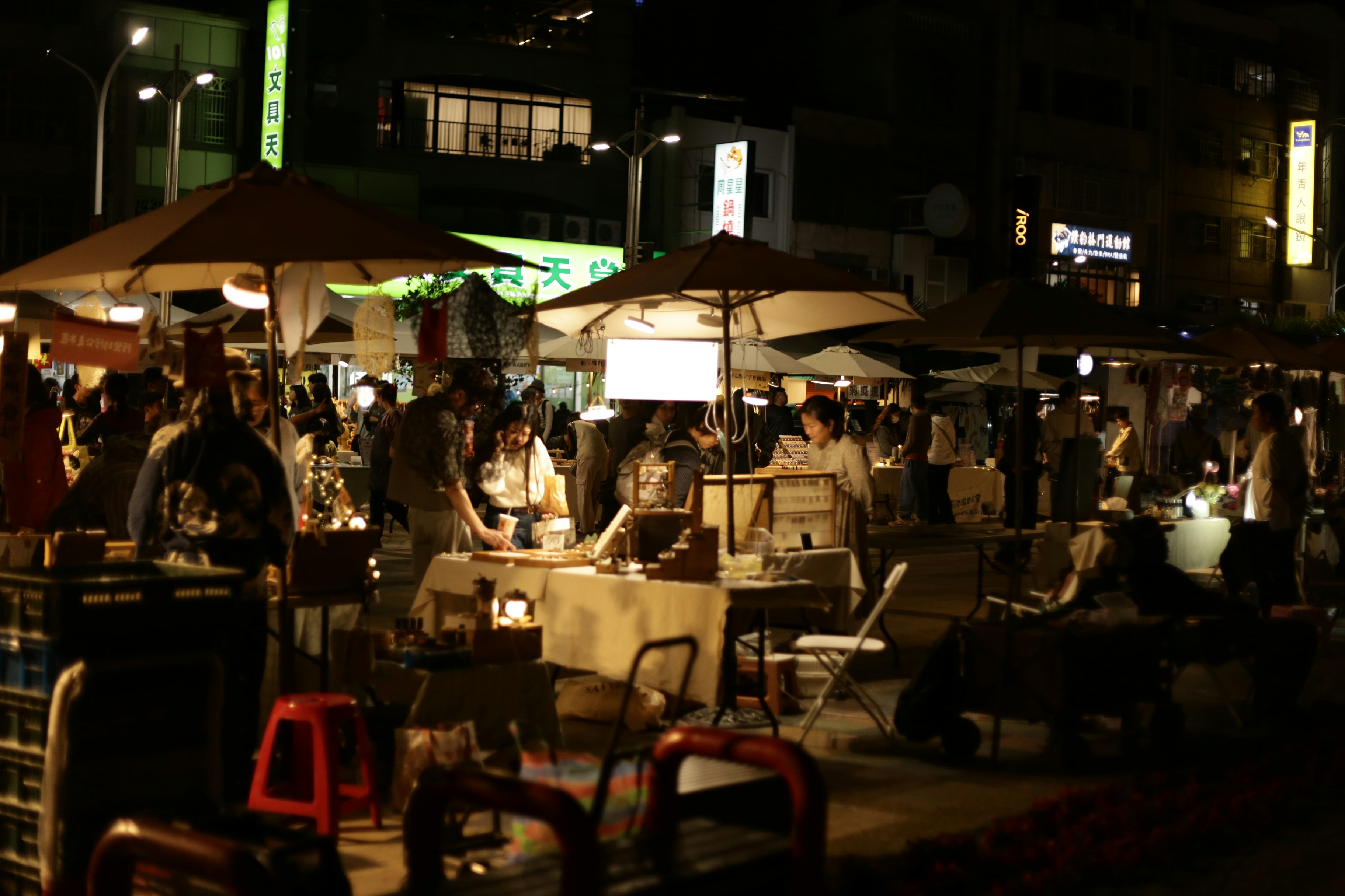 Pessoas olhando barracas em um movimentado mercado noturno.