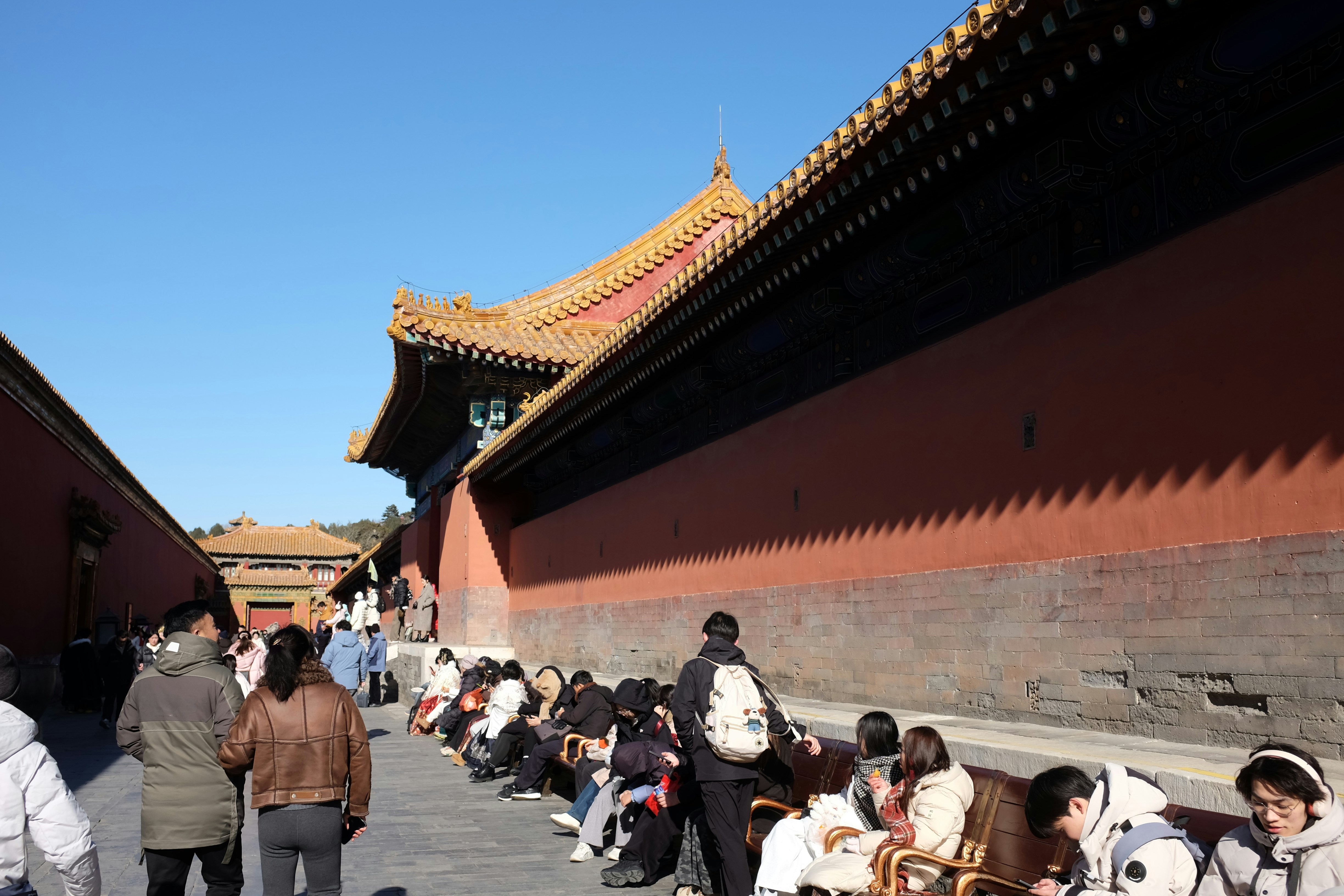 Pessoas se alinham do lado de fora do antigo palácio imperial de paredes vermelhas