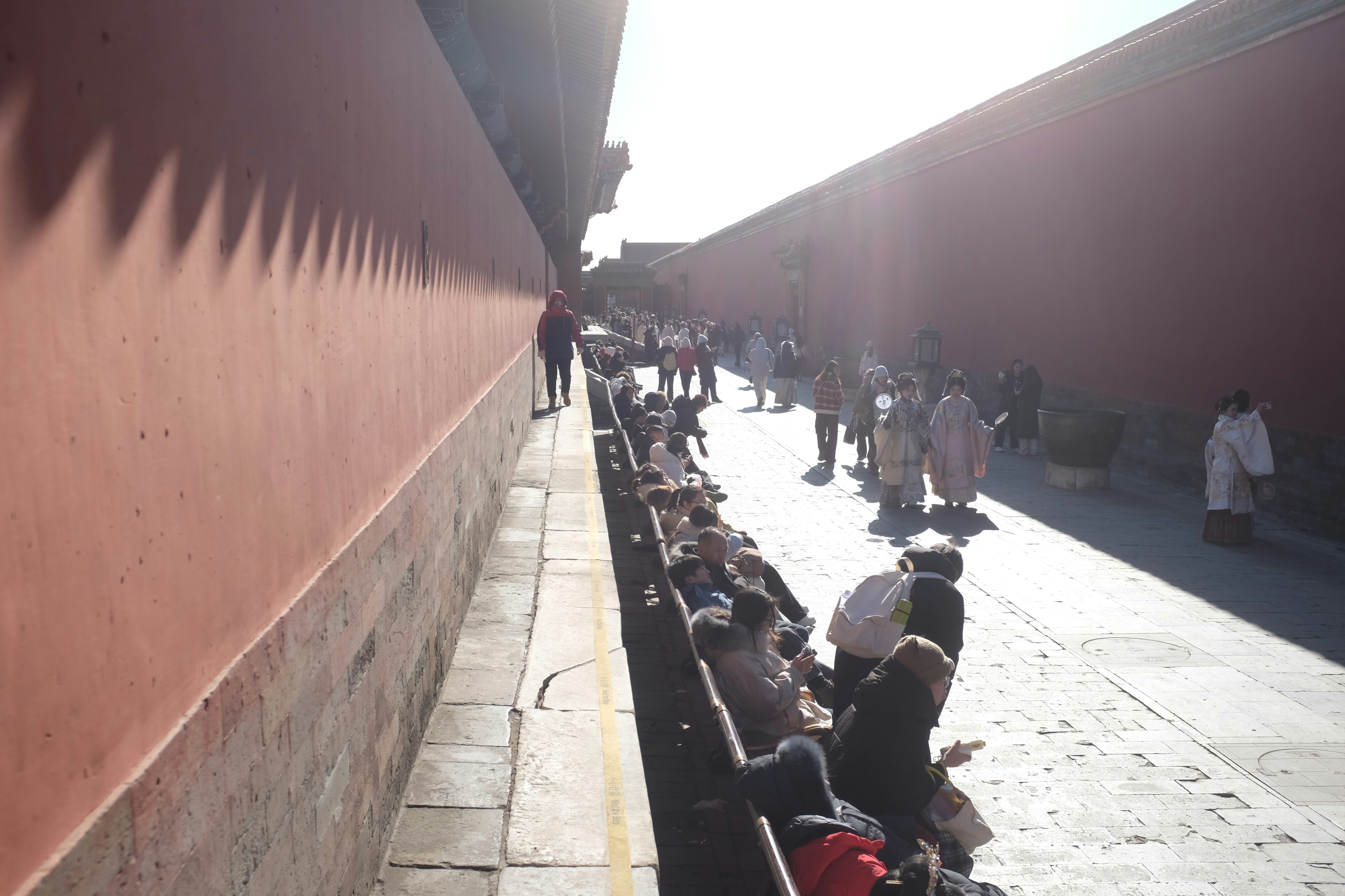 Crowd of people walking along a red wall