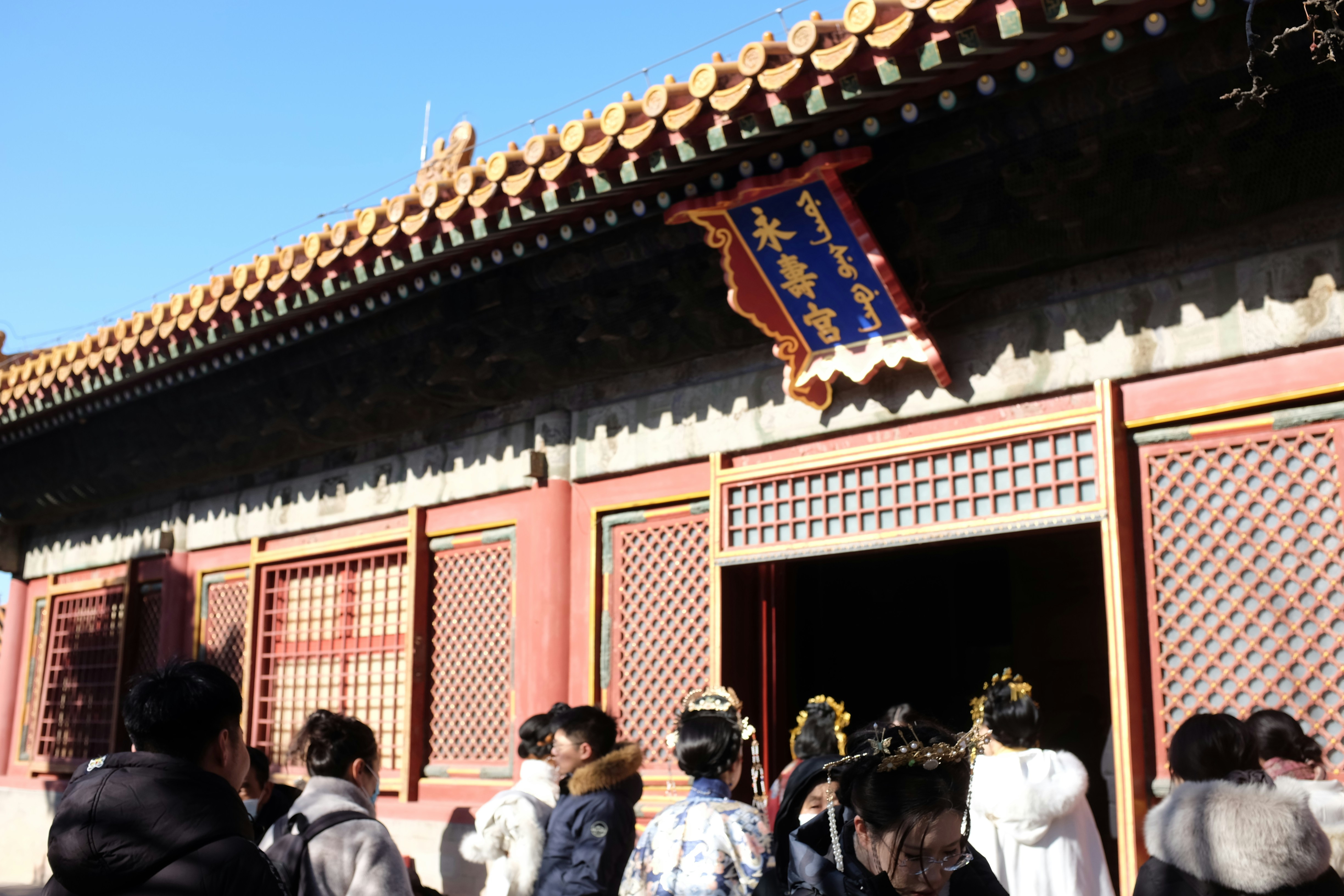 Pessoas entrando em um prédio tradicional chinês com telhado ornamentado.