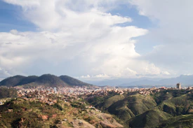 City nestled in rolling green hills under cloudy sky
