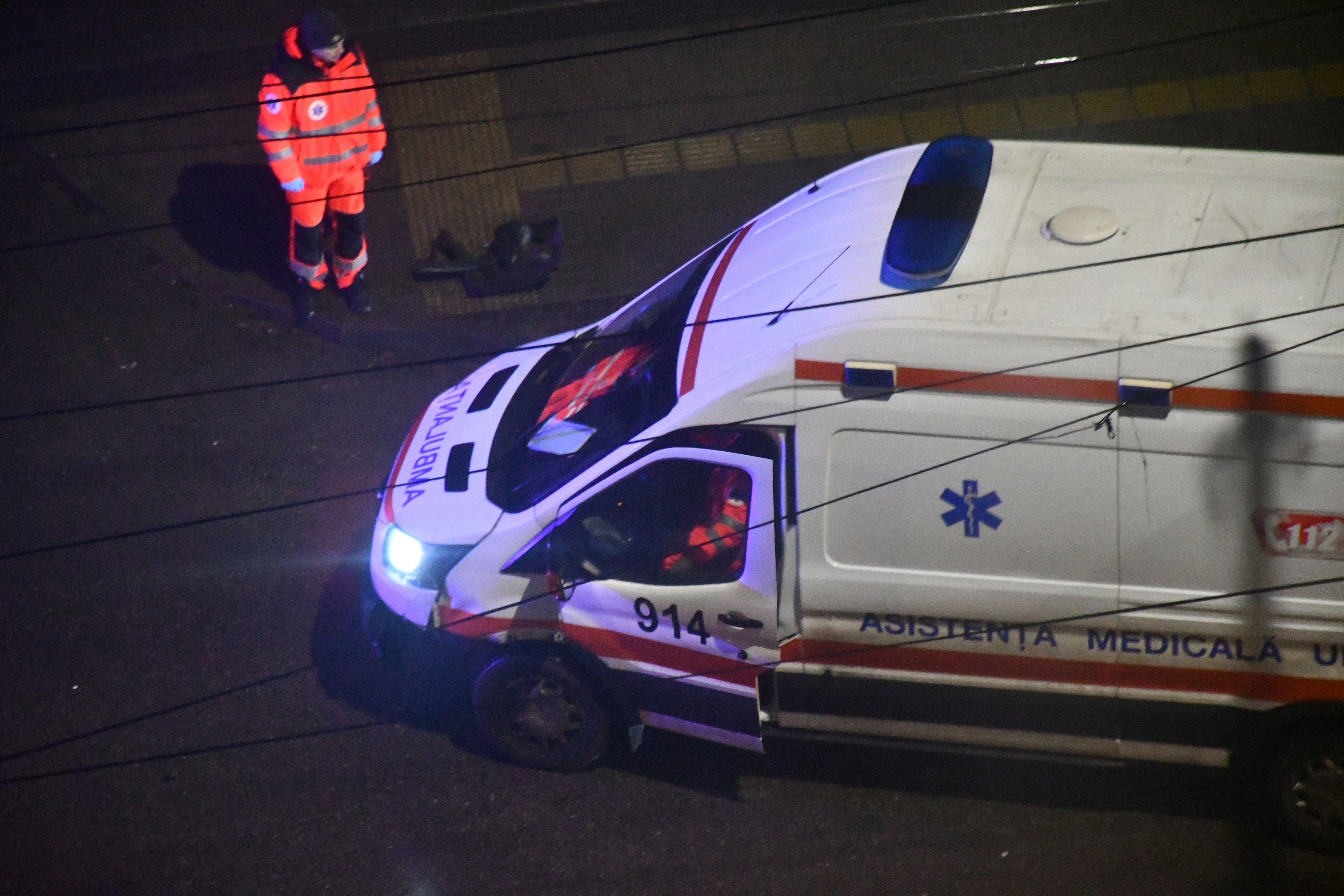 Paramedic stands near an ambulance at night.