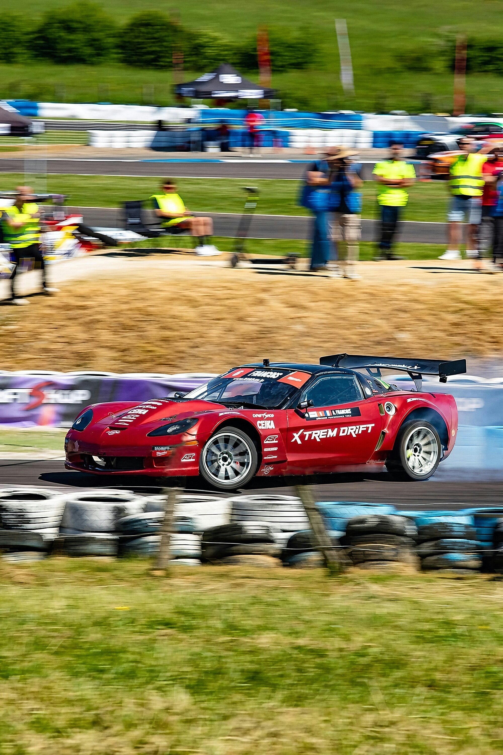 Red sports car drifting on a race track with smoke.
