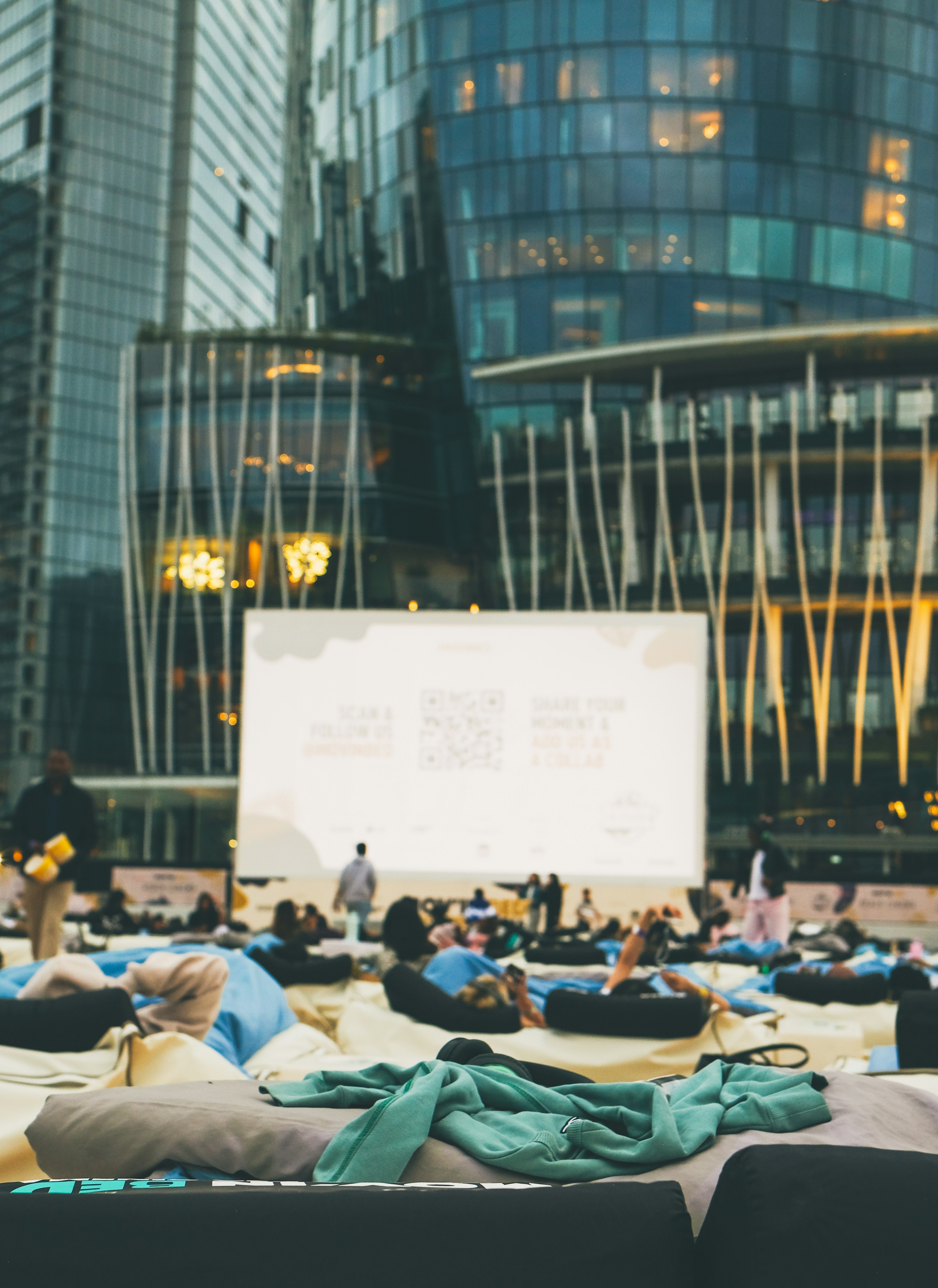 Pessoas assistem a uma exibição de filme ao ar livre em uma cidade