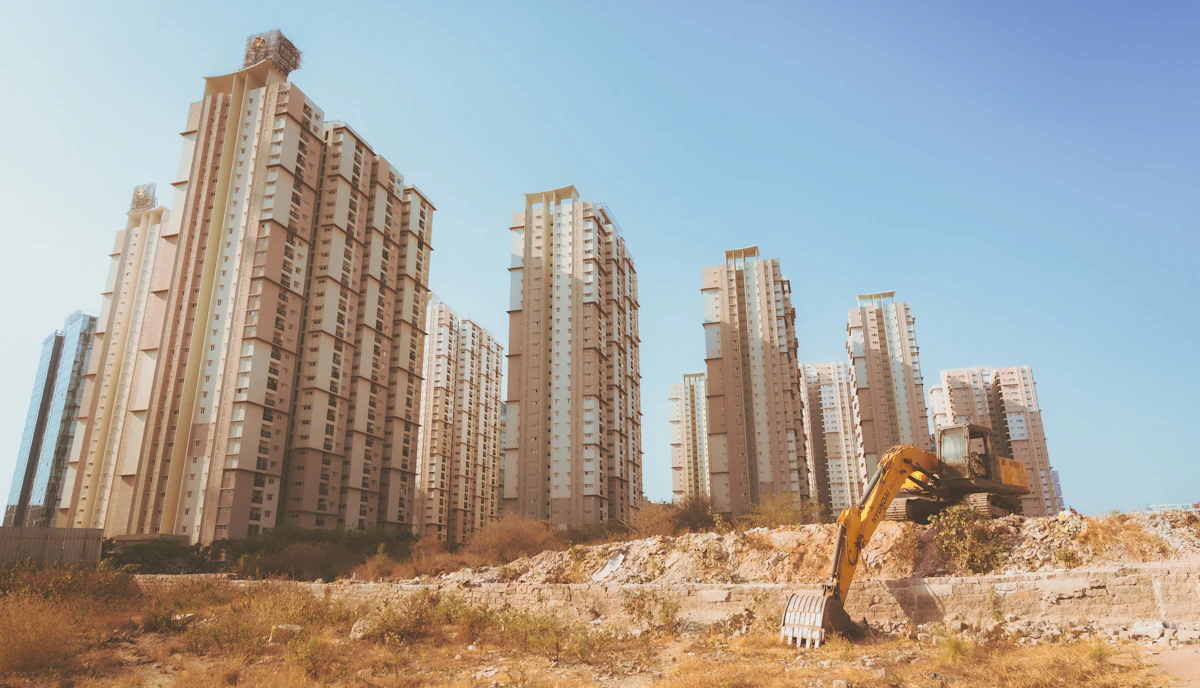 Excavator at an Indian construction site with residential towers in the background