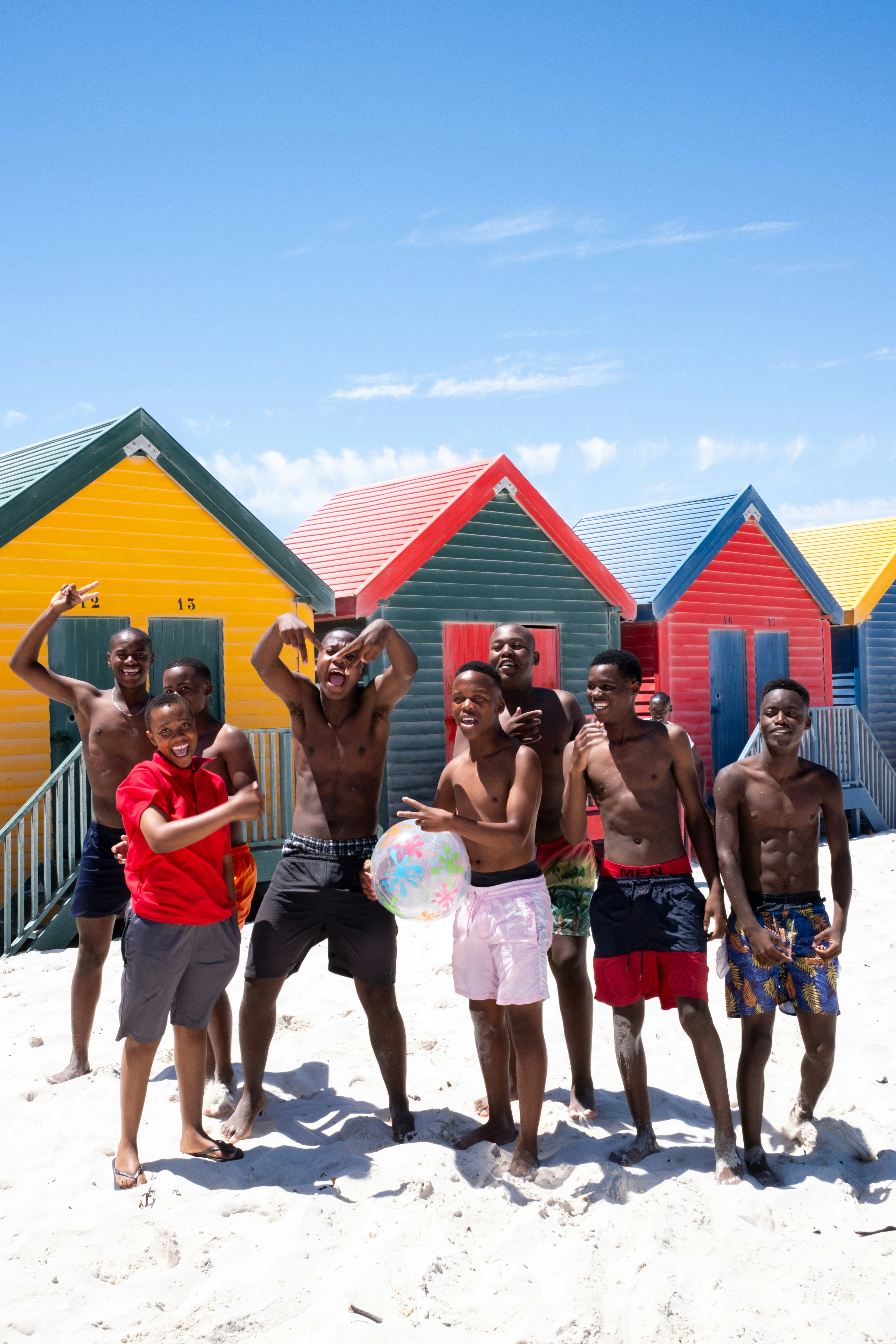 A group of young men posing on a sandy beach.