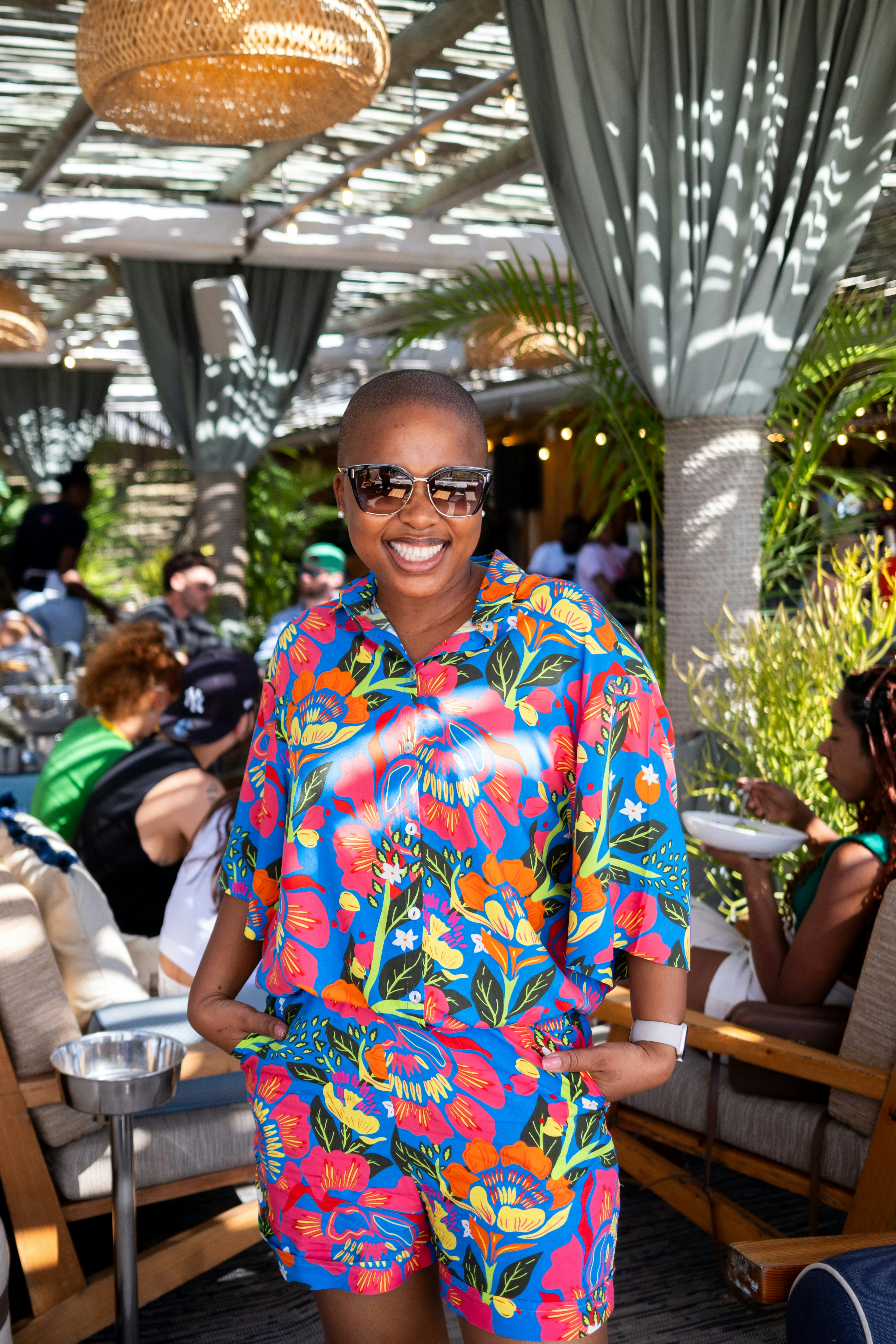 A smiling woman in a colorful floral outfit outdoors.