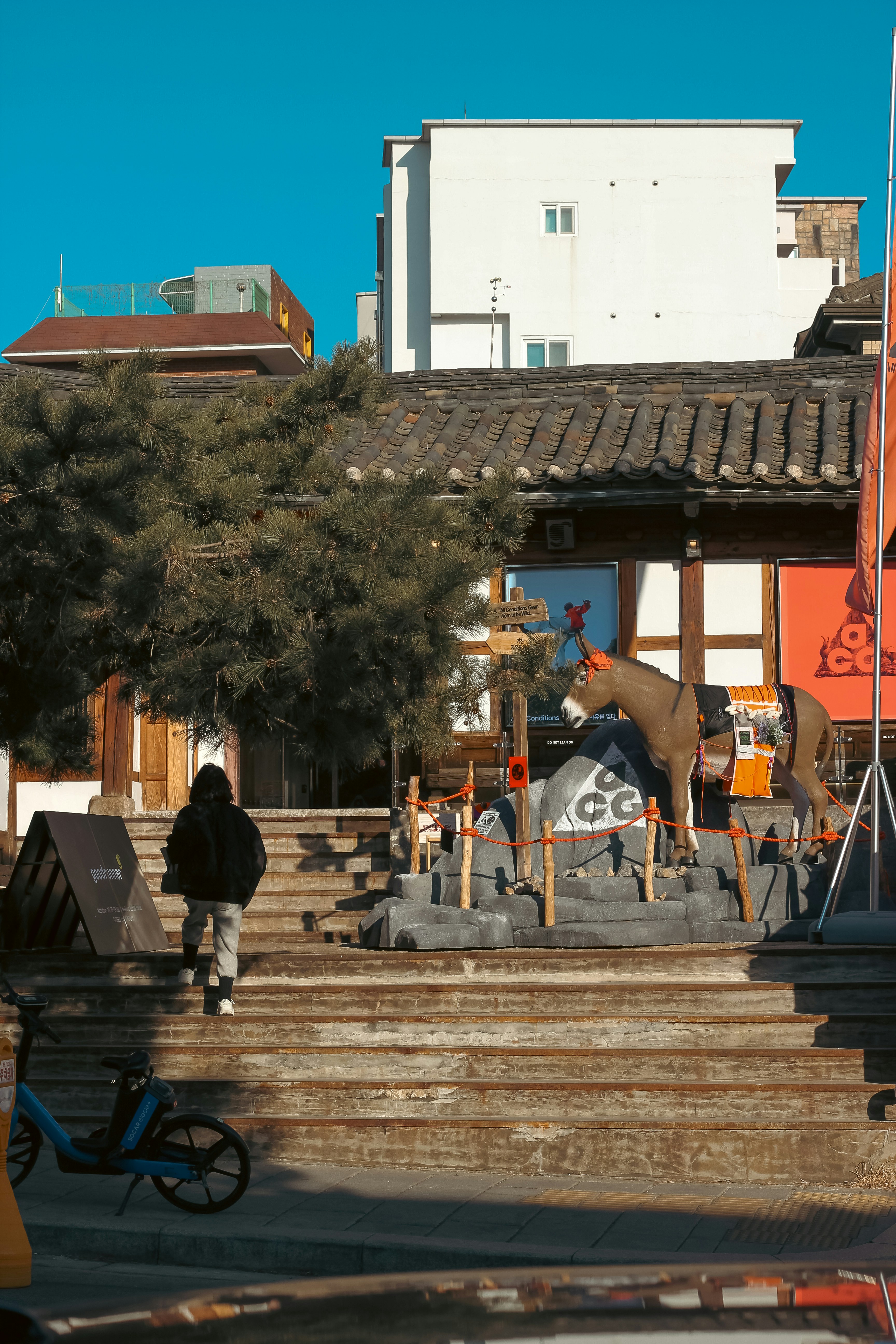 Person walks up stairs towards a horse sculpture.