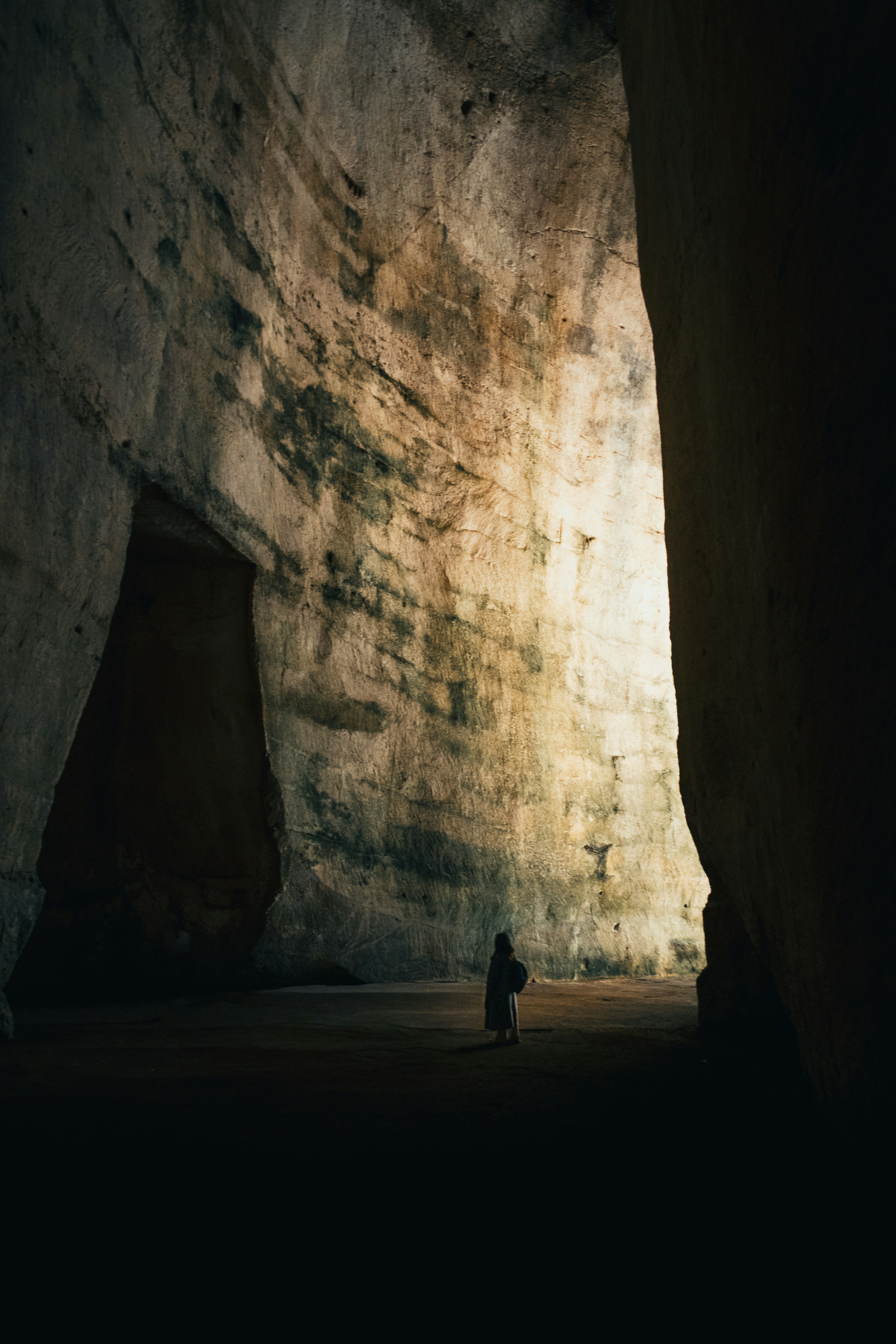A person stands silhouetted in a vast, illuminated cave.