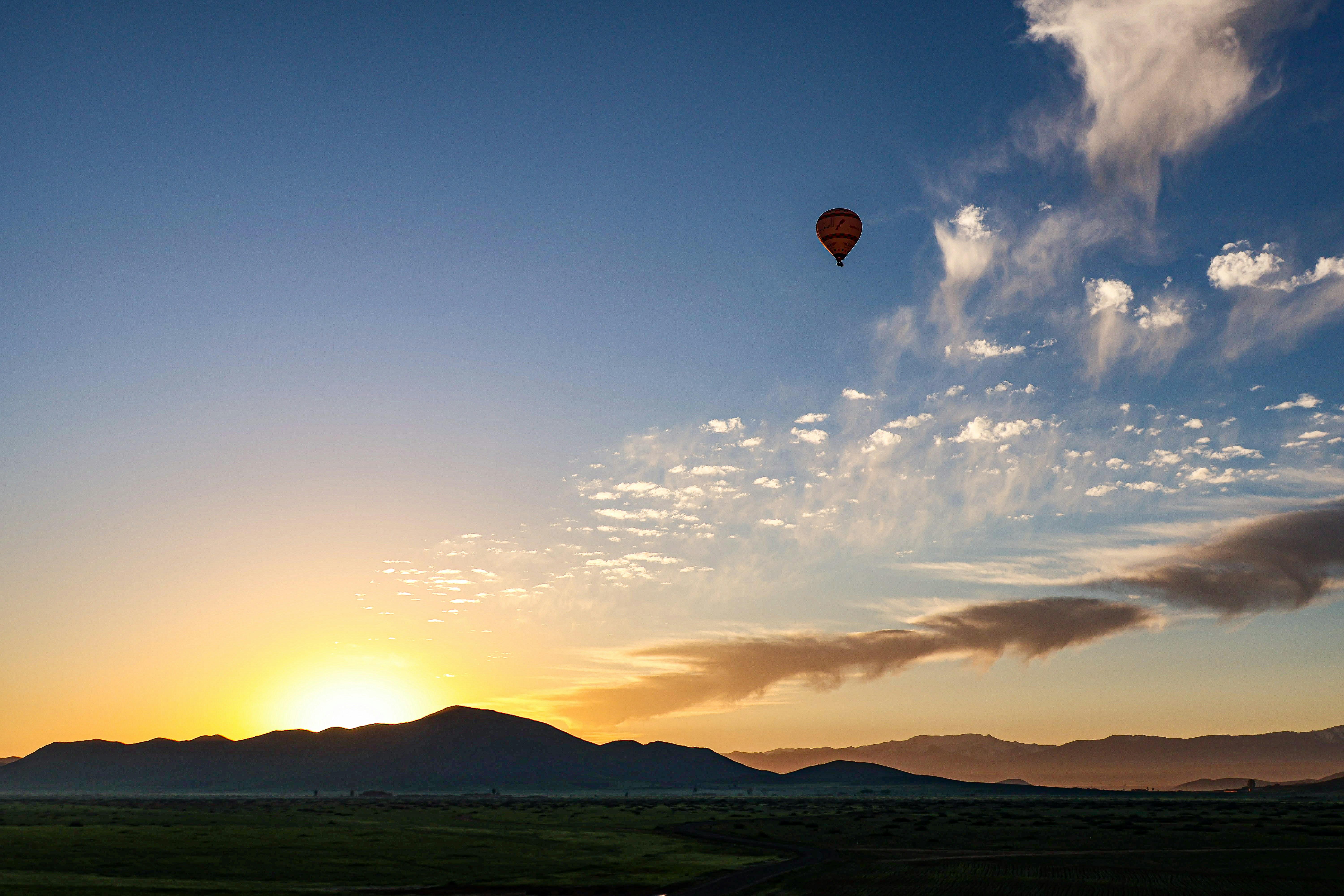 Globo aerostático sobrevuela montañas al amanecer.