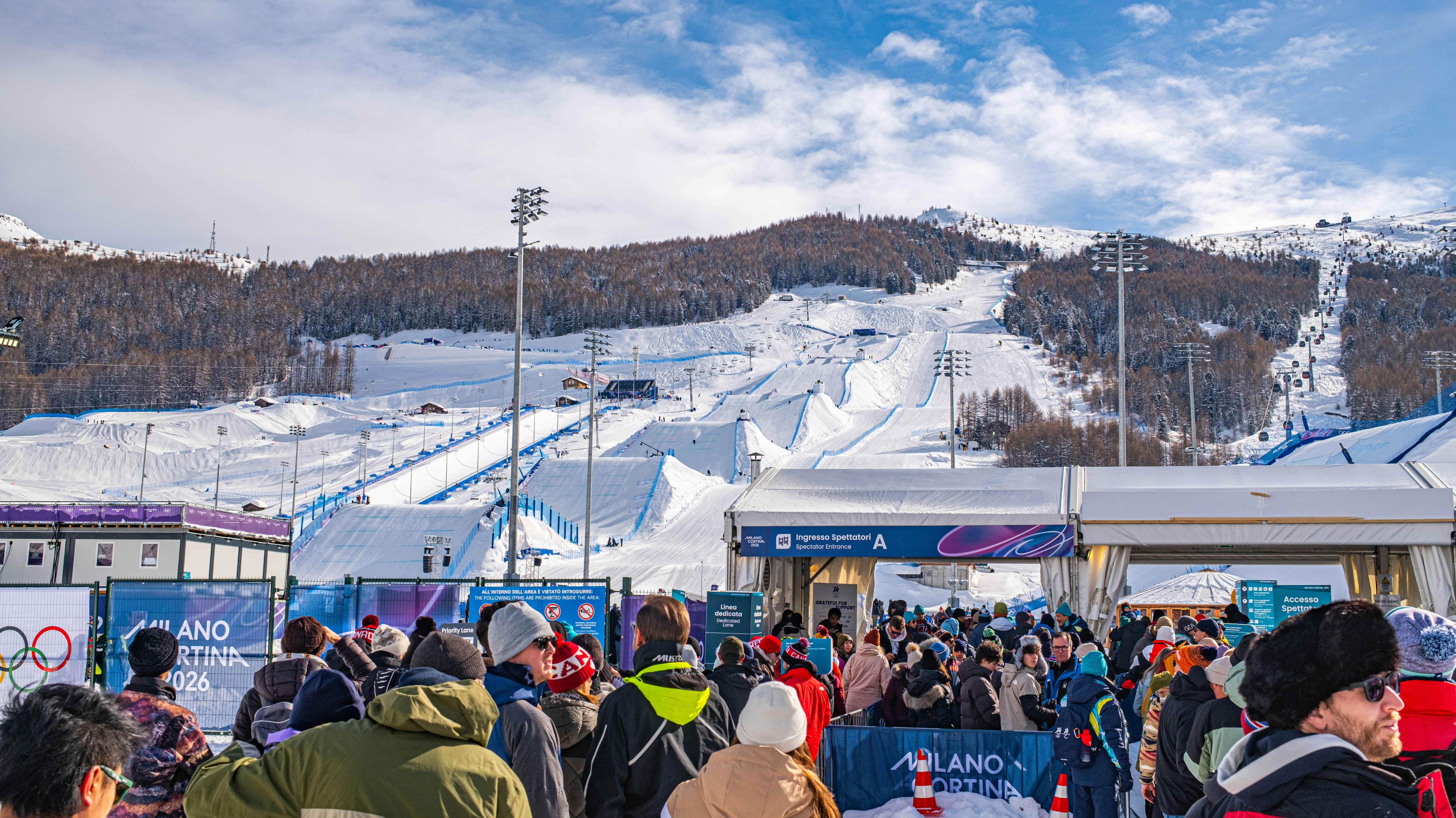 Crowd gathered at a snowy ski resort with mountains behind