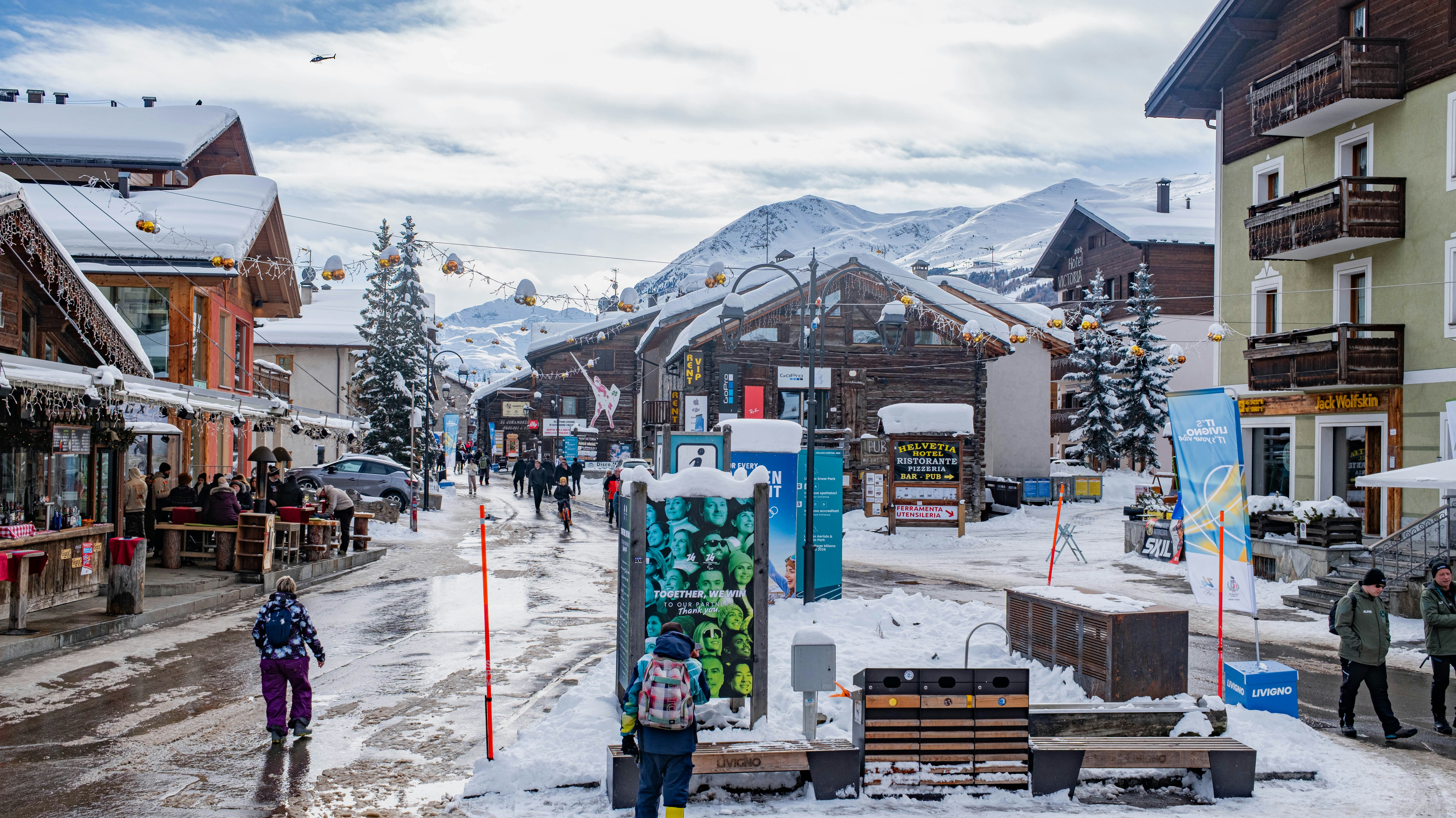 Snowy street in a mountain village with shops and people