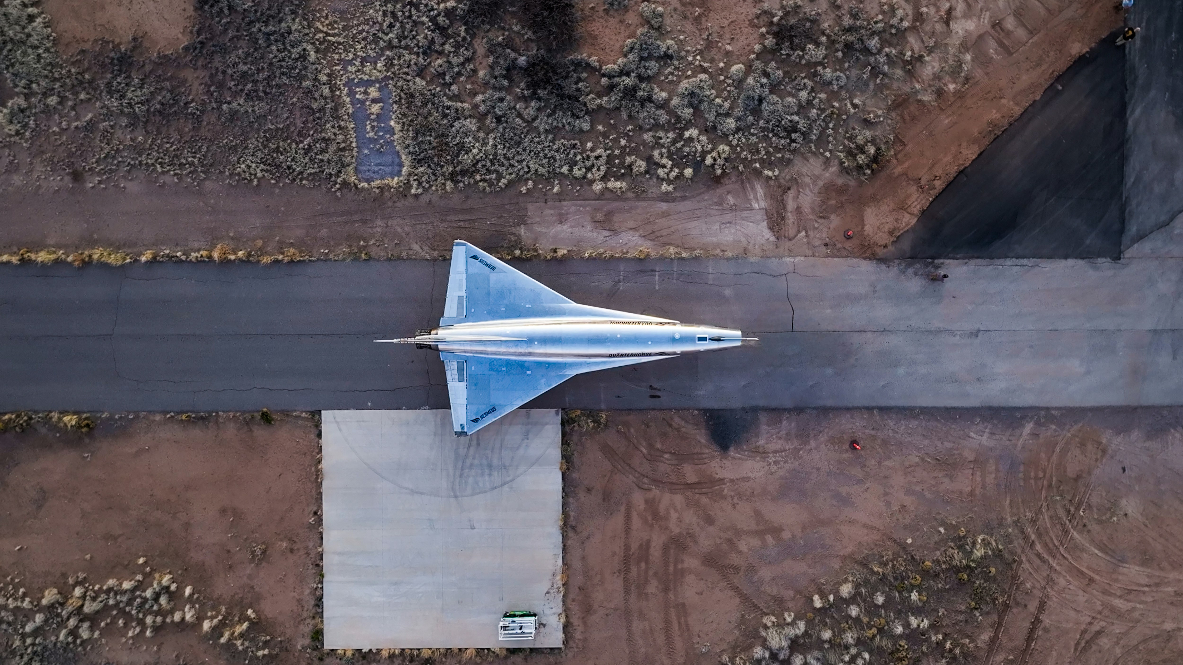 A sleek silver jet rests on a runway.