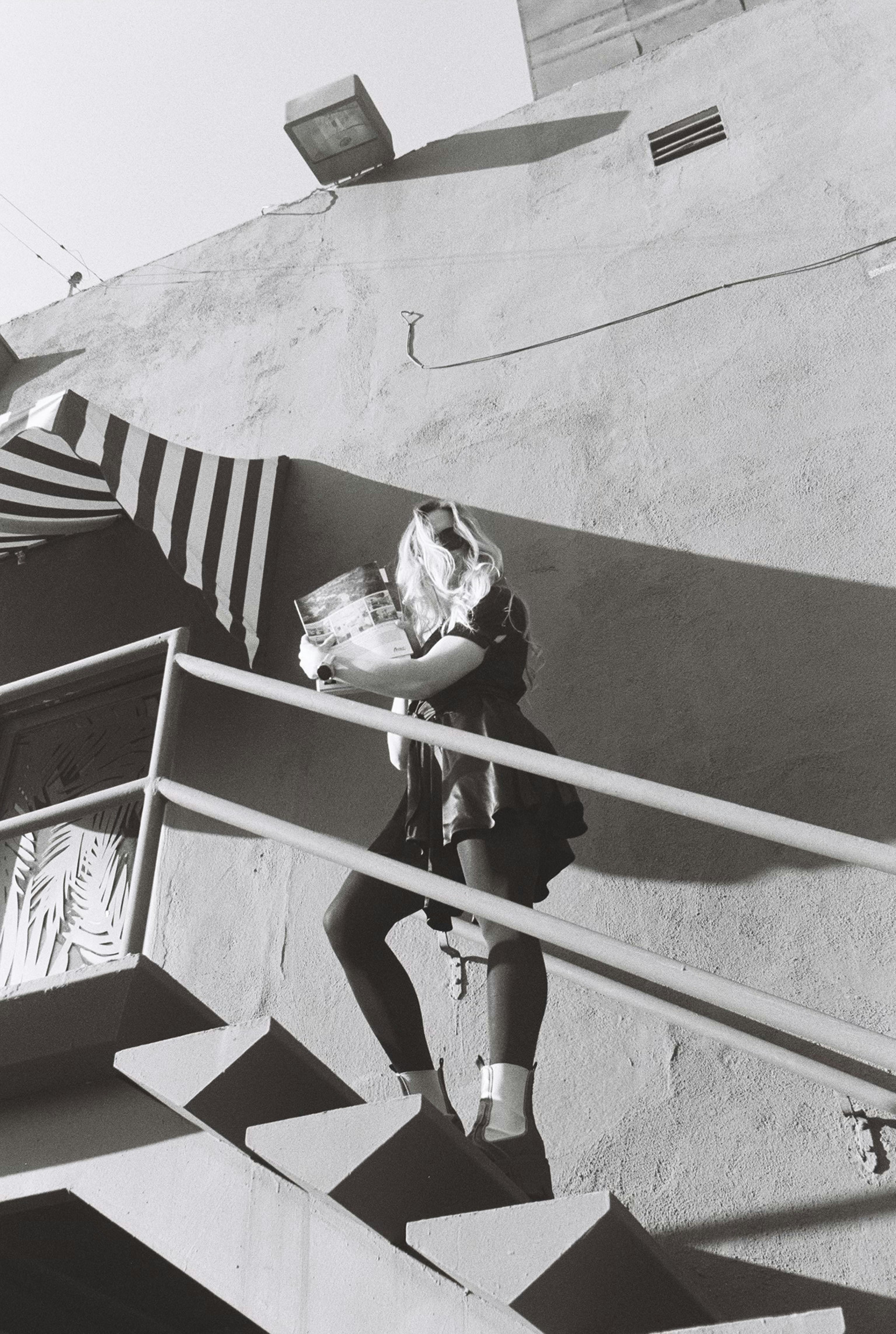 Woman carrying magazines up outdoor stairs
