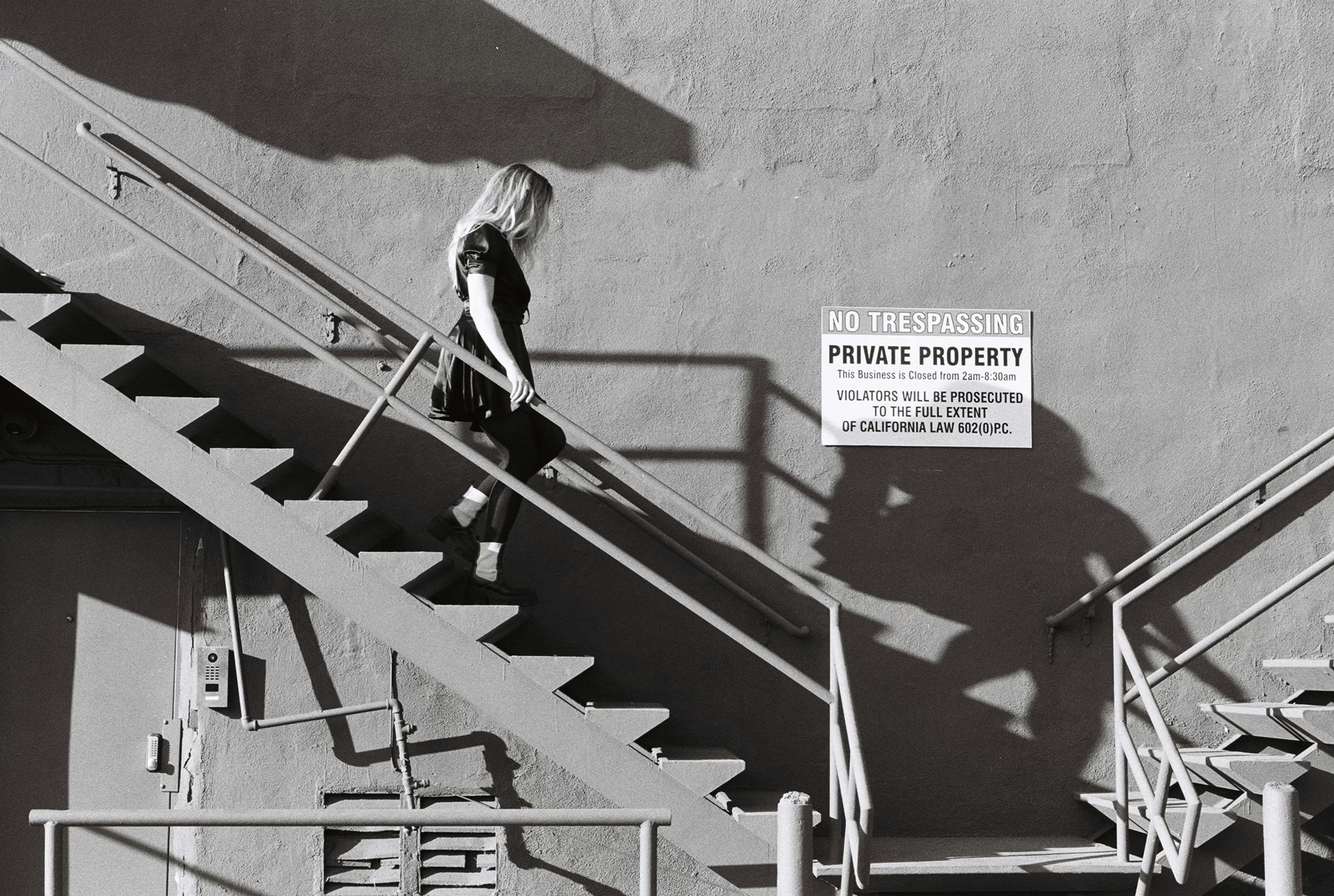 Woman walking down outdoor metal stairs near sign