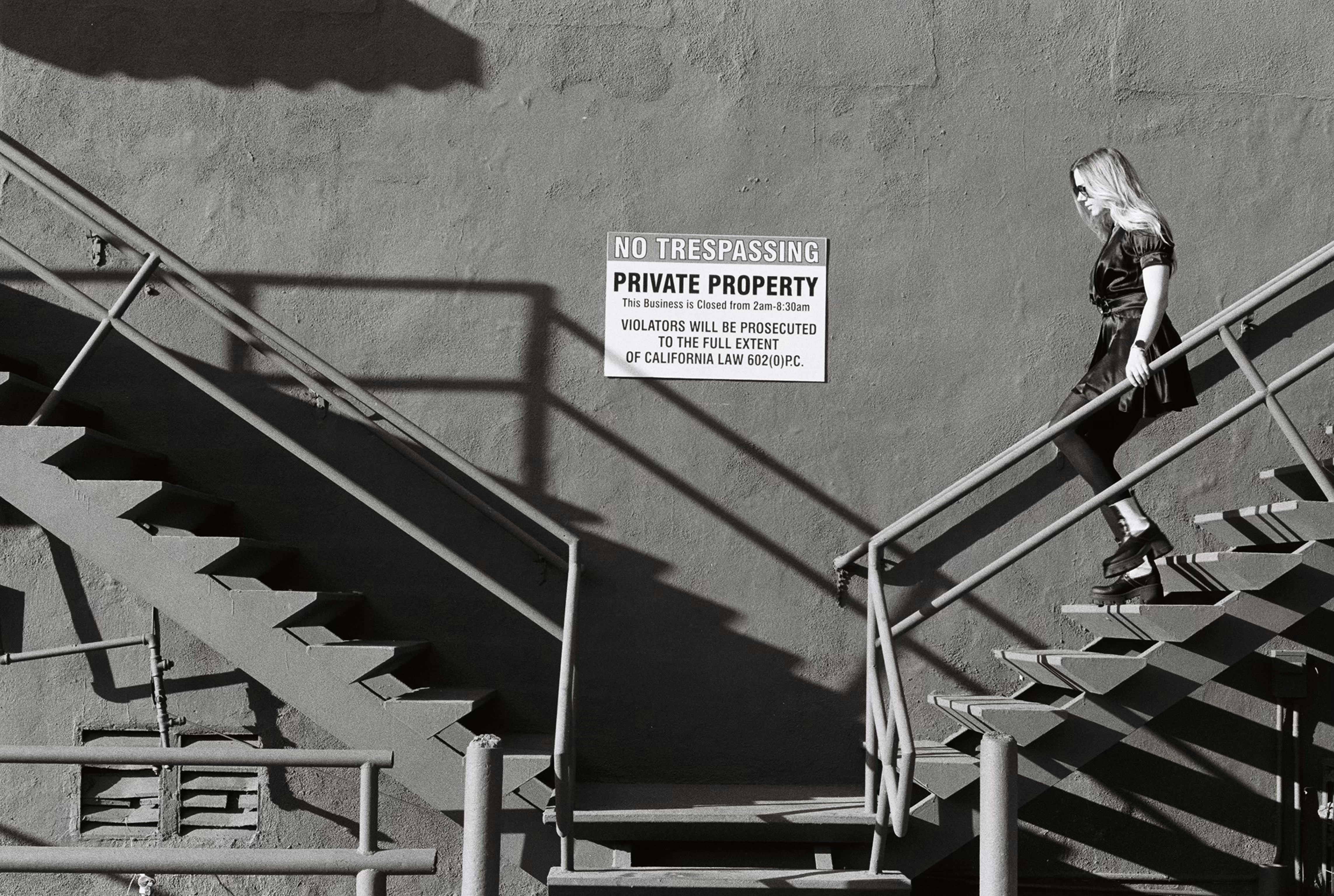 Woman walking down metal stairs near sign