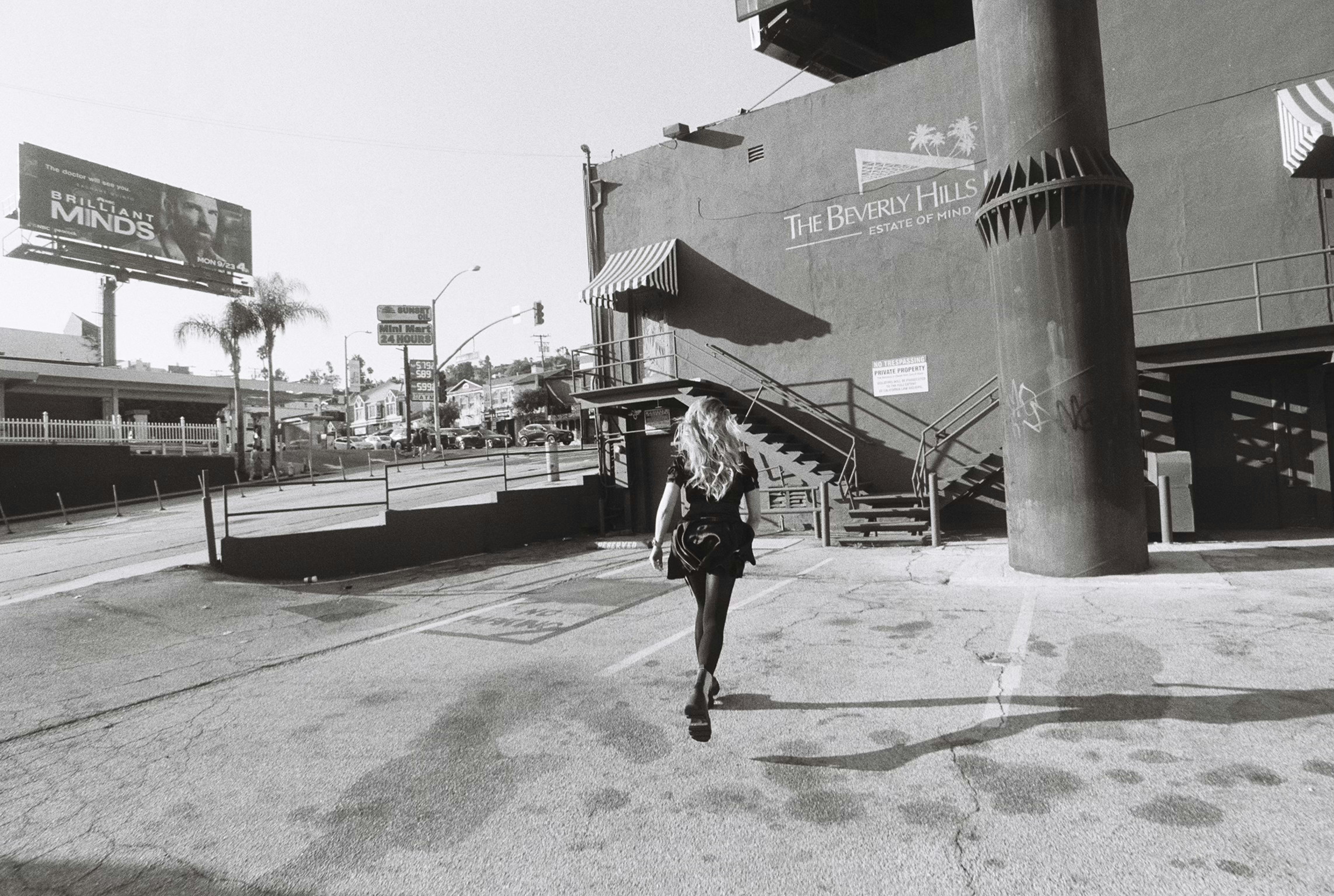 Woman walking away from camera towards building
