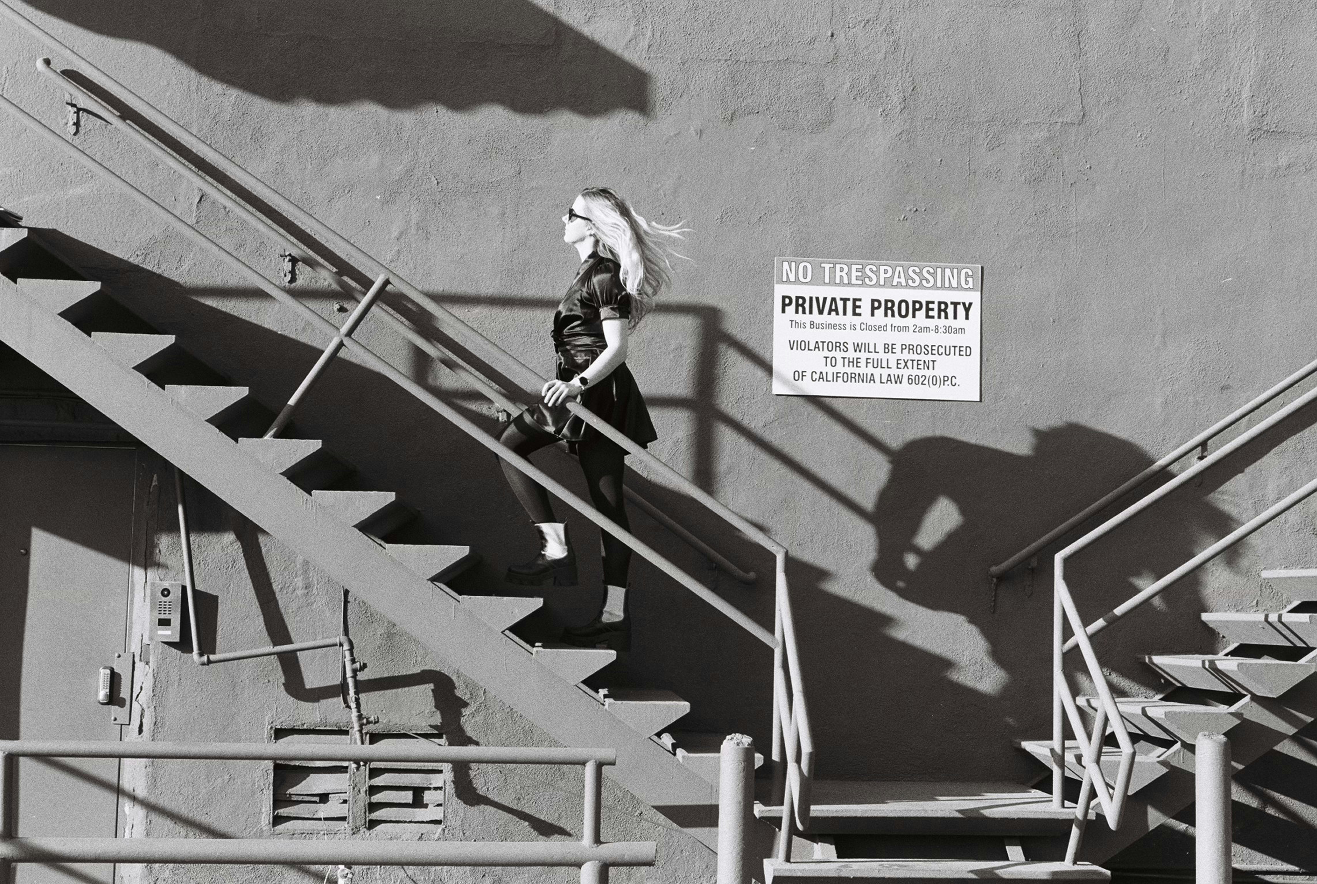 Woman walking up outdoor metal stairs casting shadows