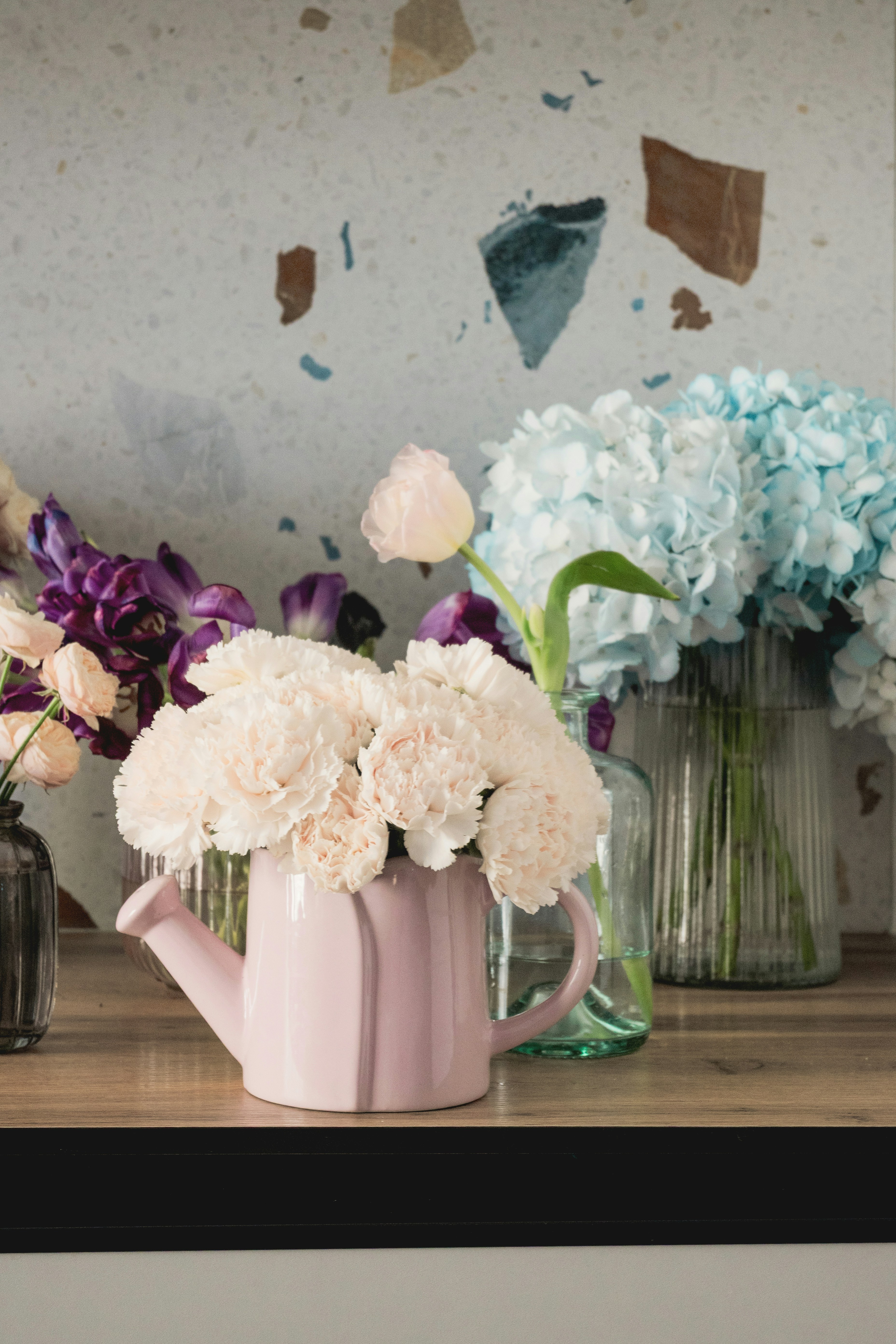 Pink watering can filled with white flowers.