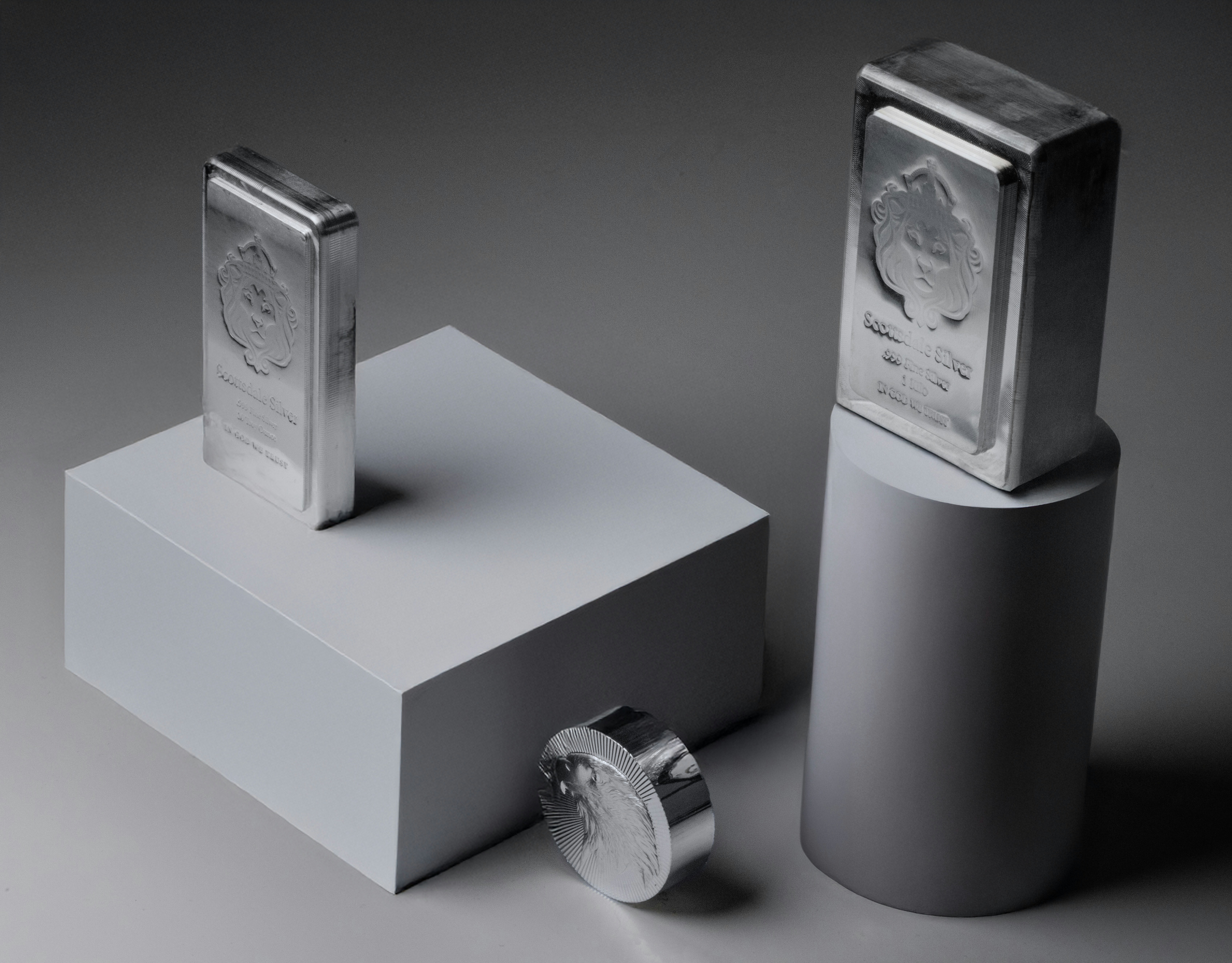 Two silver bars and a coin on pedestals