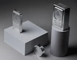 Two silver bars and a coin on pedestals