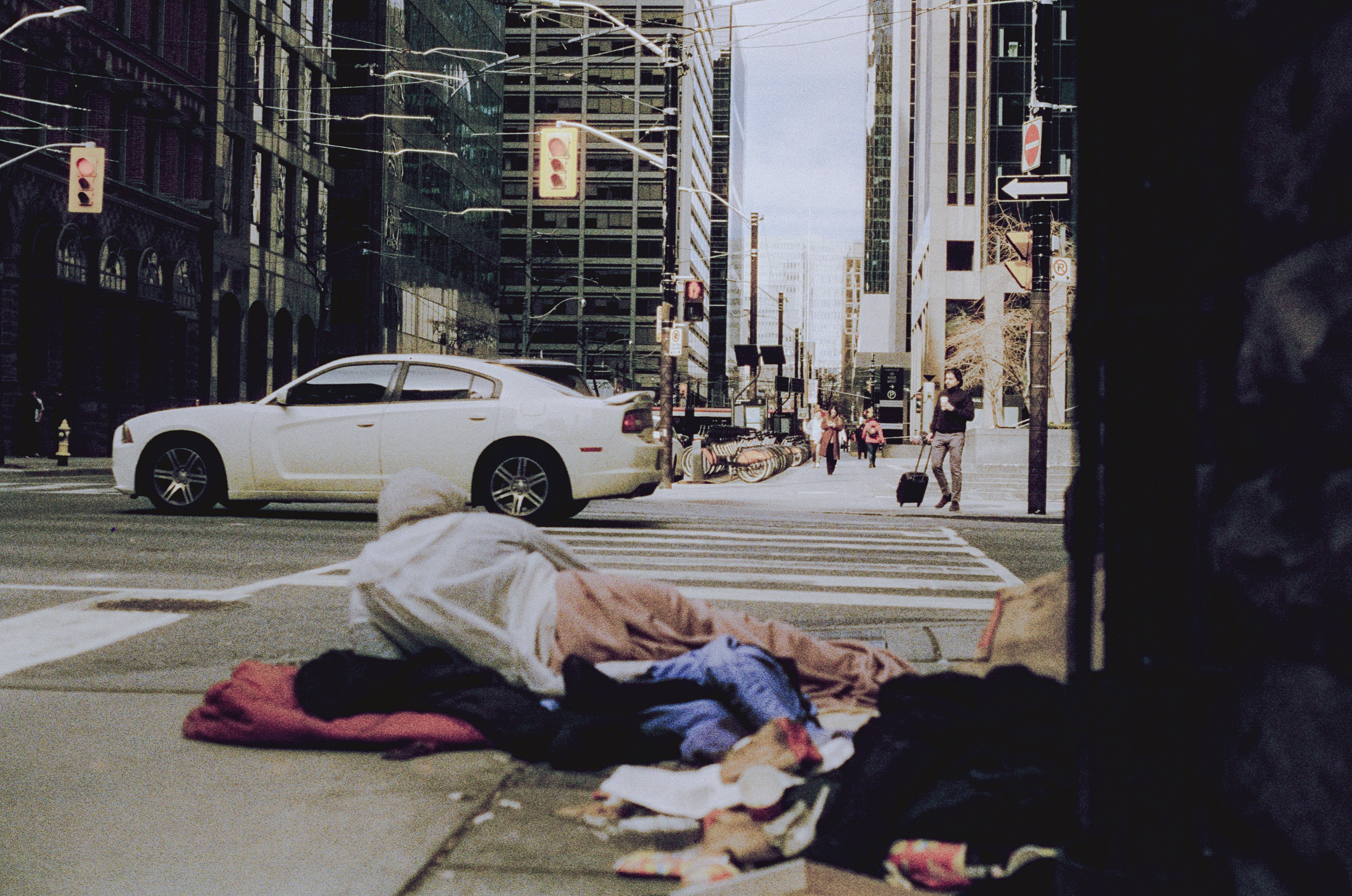 Persona sin hogar durmiendo en la acera de la ciudad con tráfico