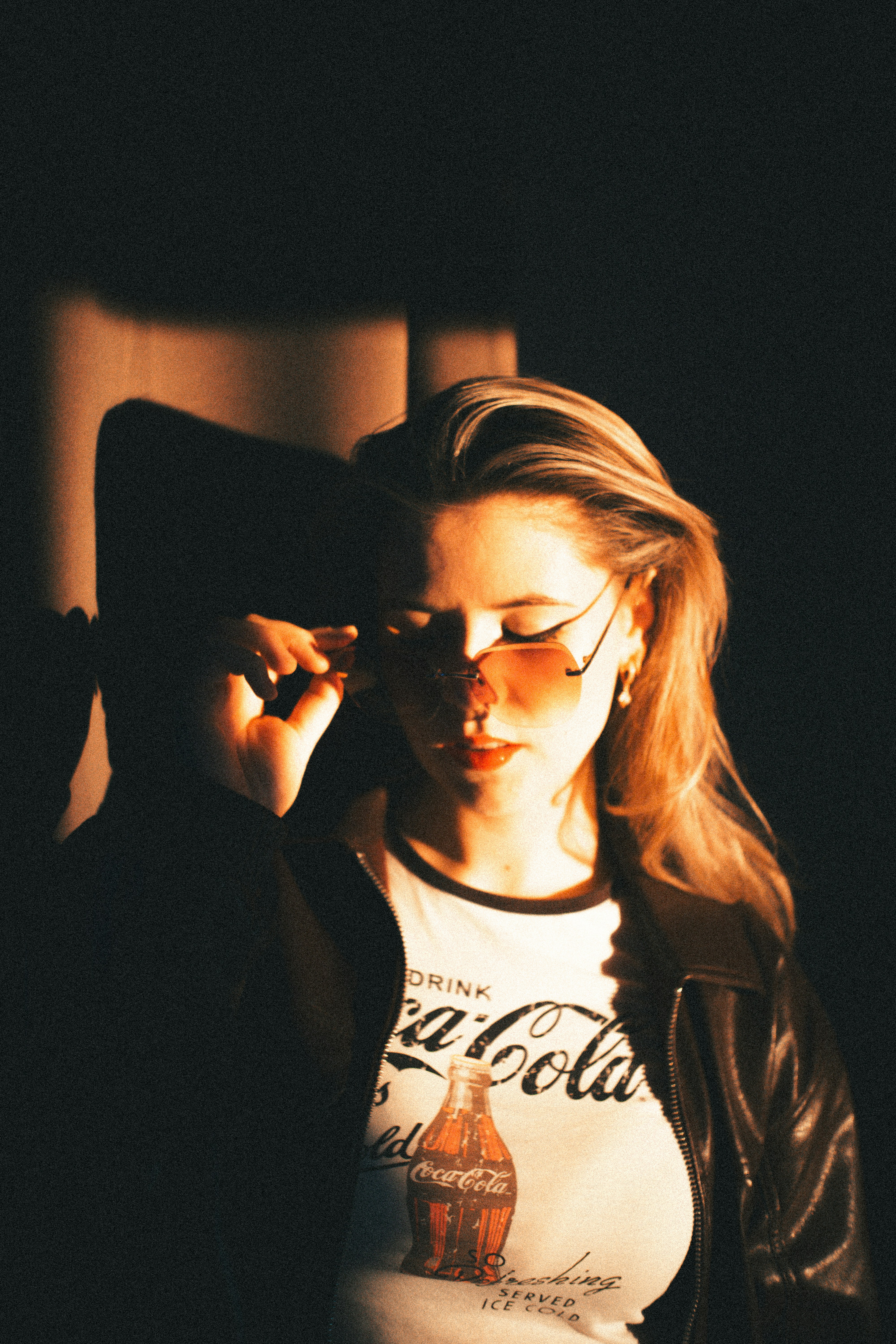 Woman in sunglasses adjusts them against dark background