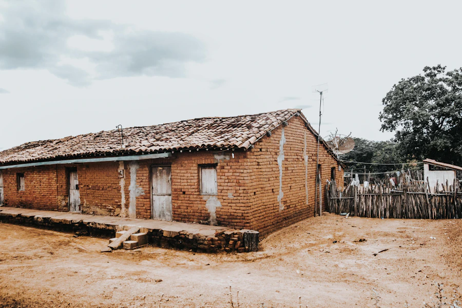Casa real rústica em tom terracota, com telhado de telhas e cerca de madeira