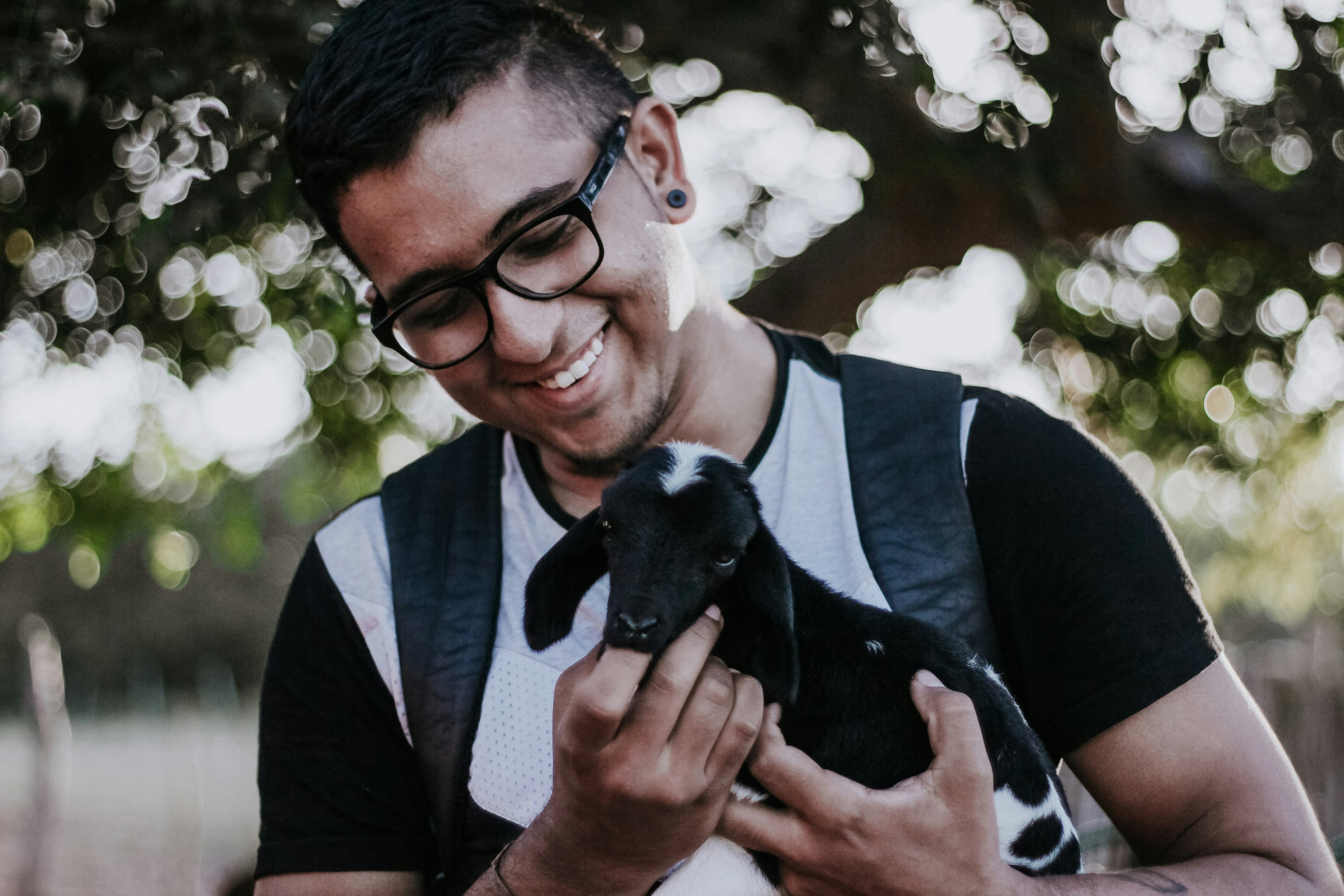 Man holding a small goat outdoors