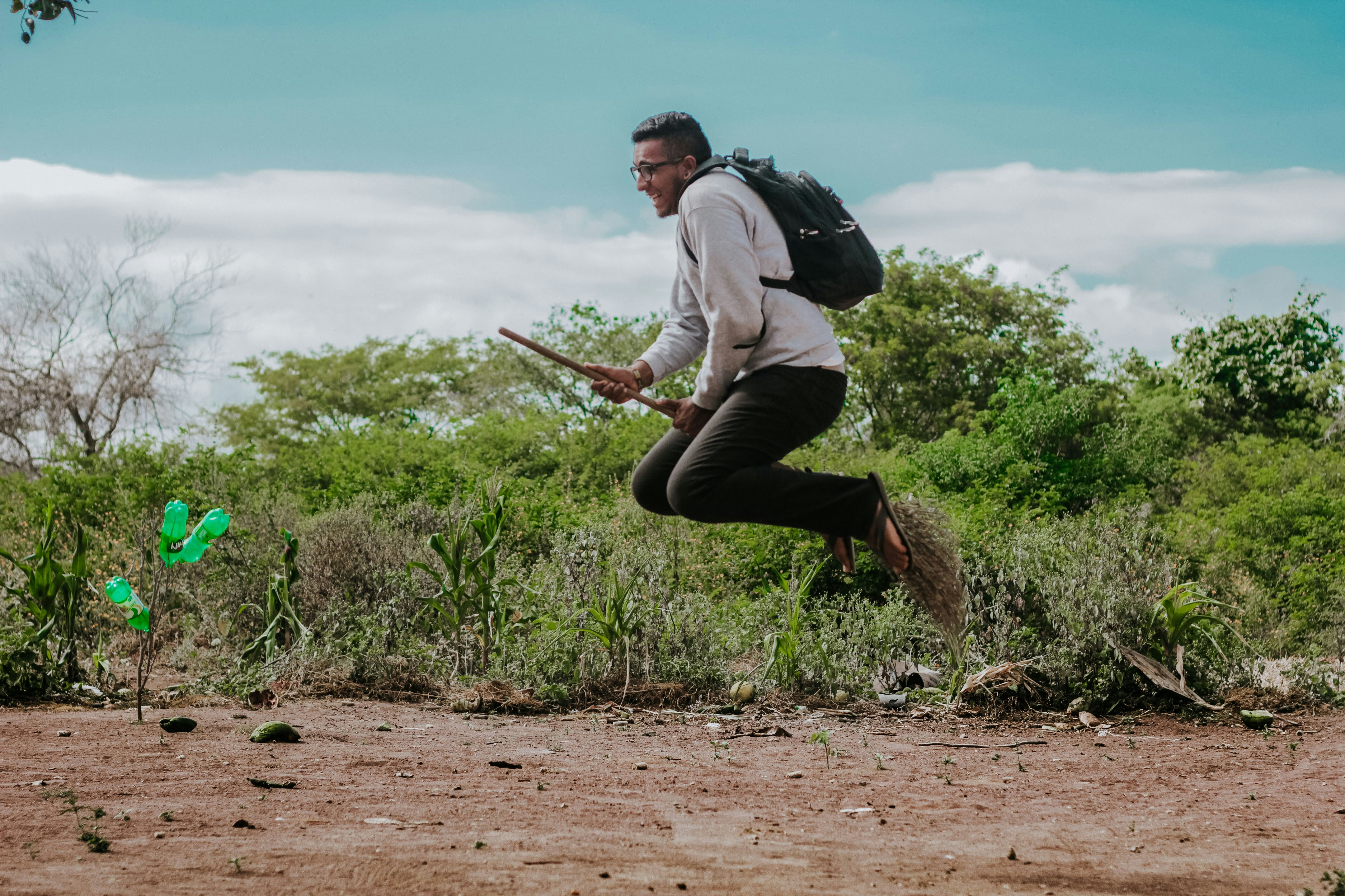 Man flying on a broomstick with a backpack