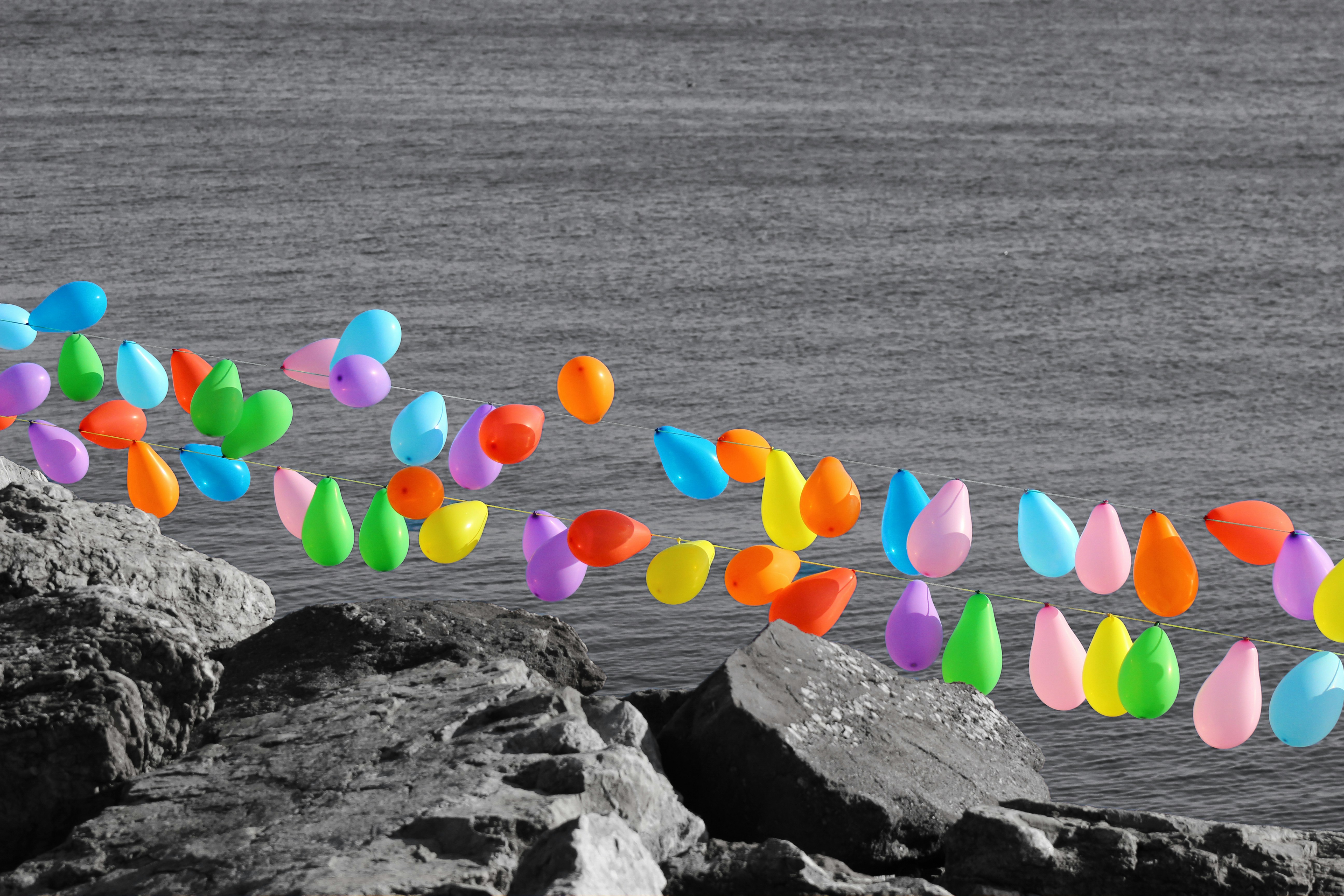 Bunte Ballons, die über felsigem Ufer und Wasser schweben