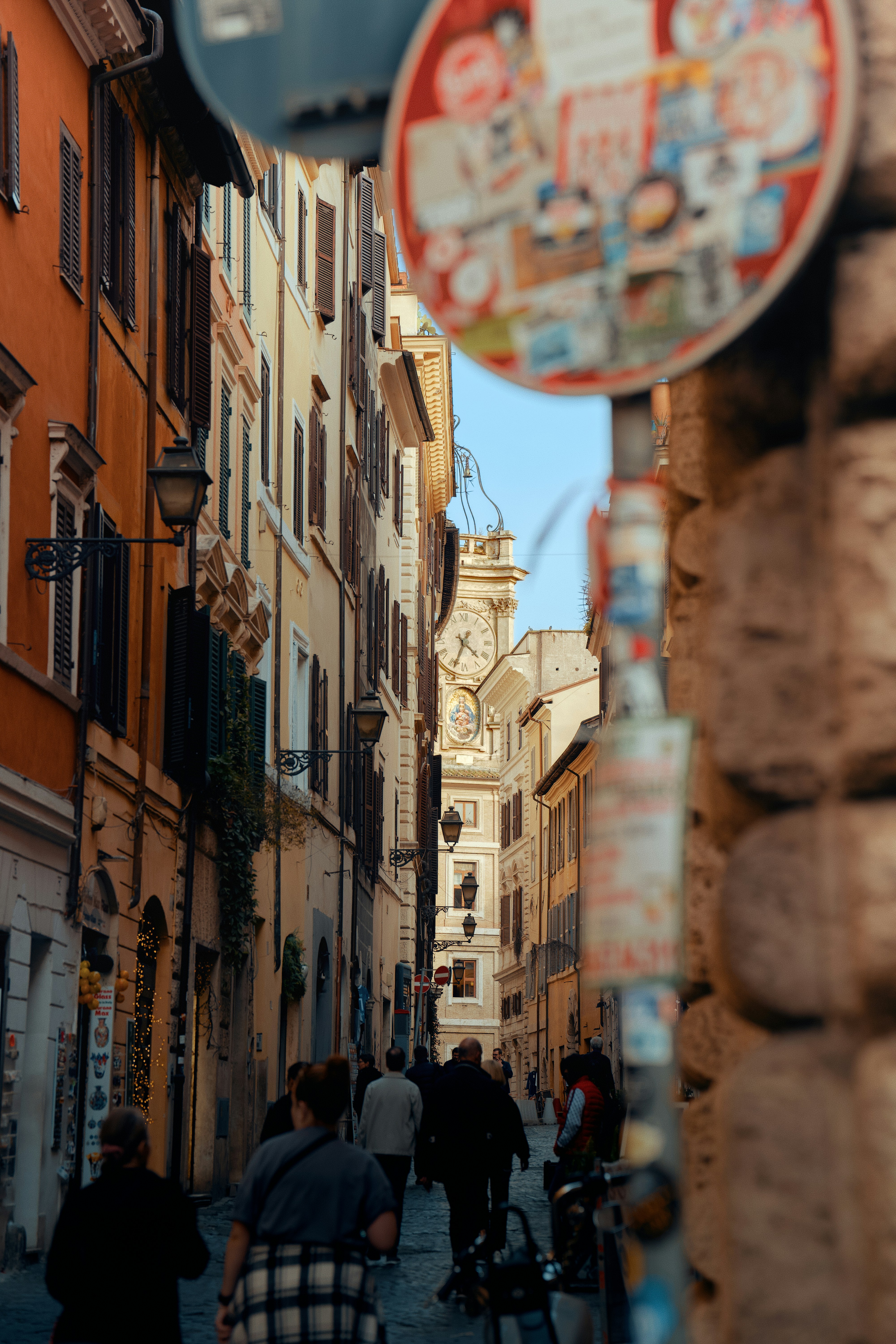 People walking down a narrow european street with buildings.