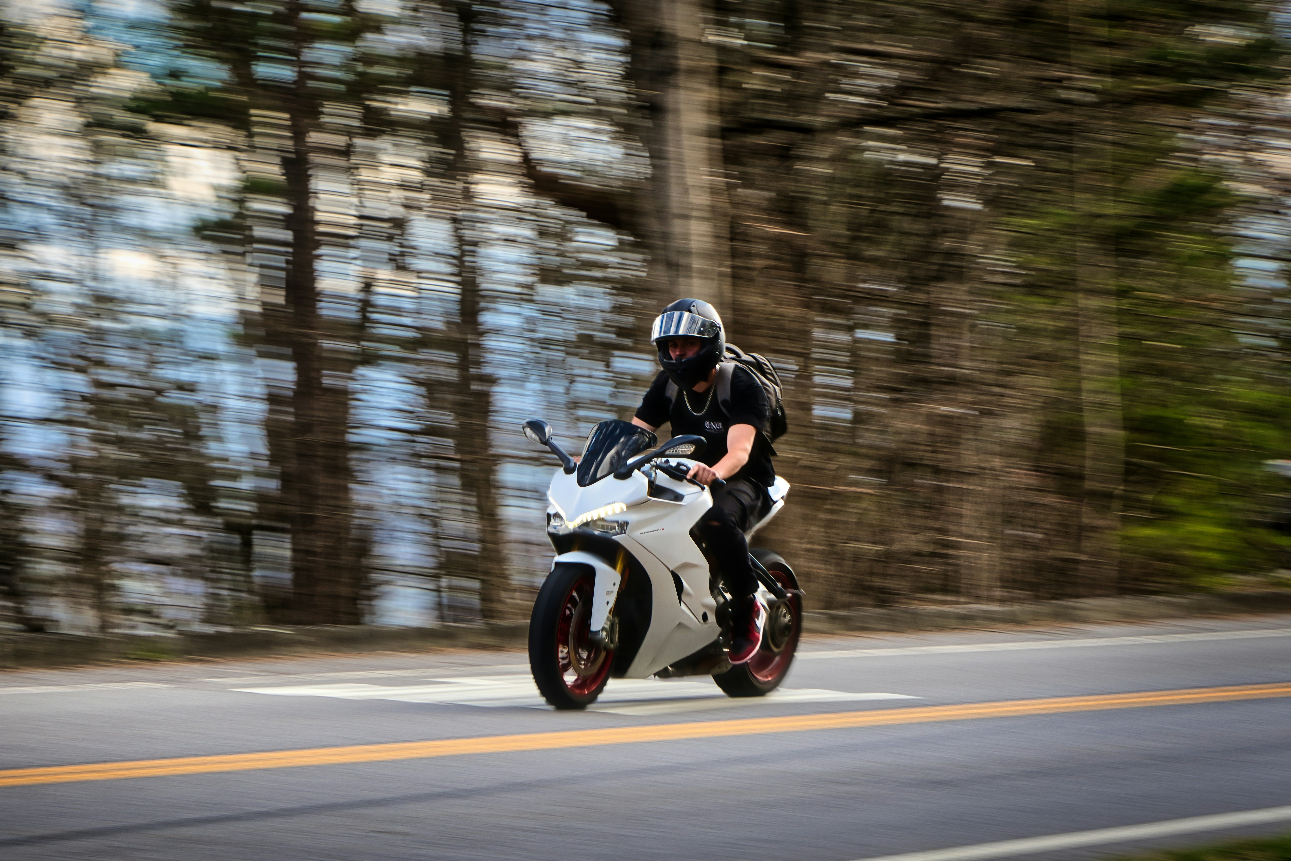Une personne conduit une moto blanche sur une route.