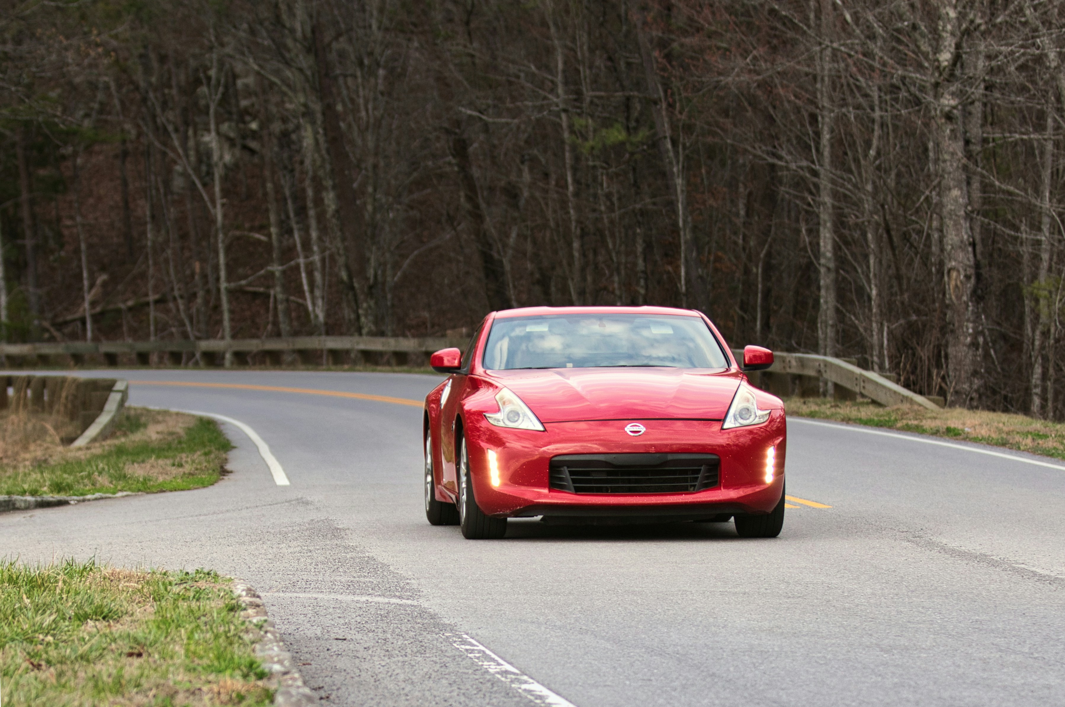 Voiture de sport rouge roulant sur une route sinueuse.