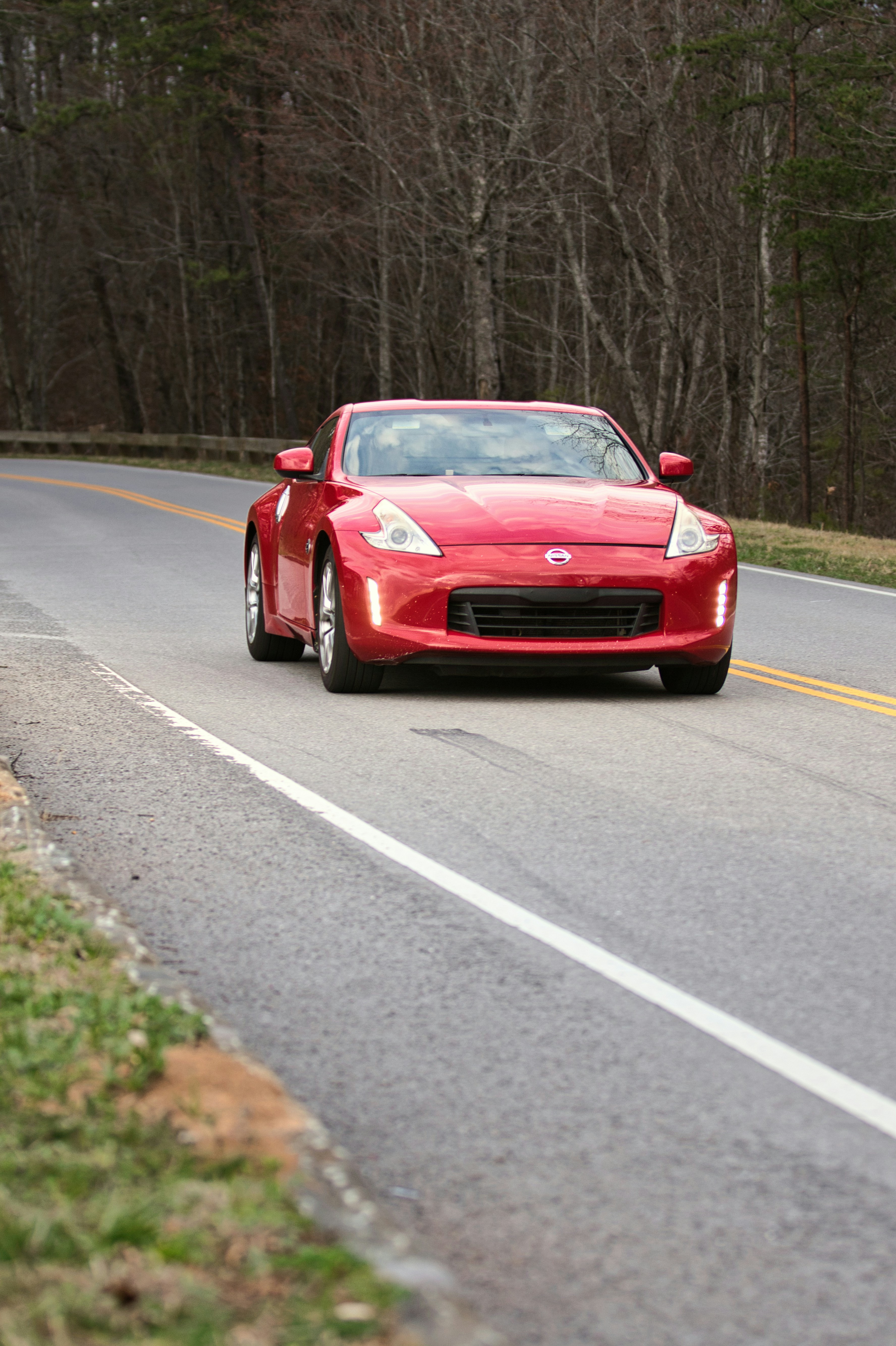Une voiture de sport rouge roule sur une route goudronnée.