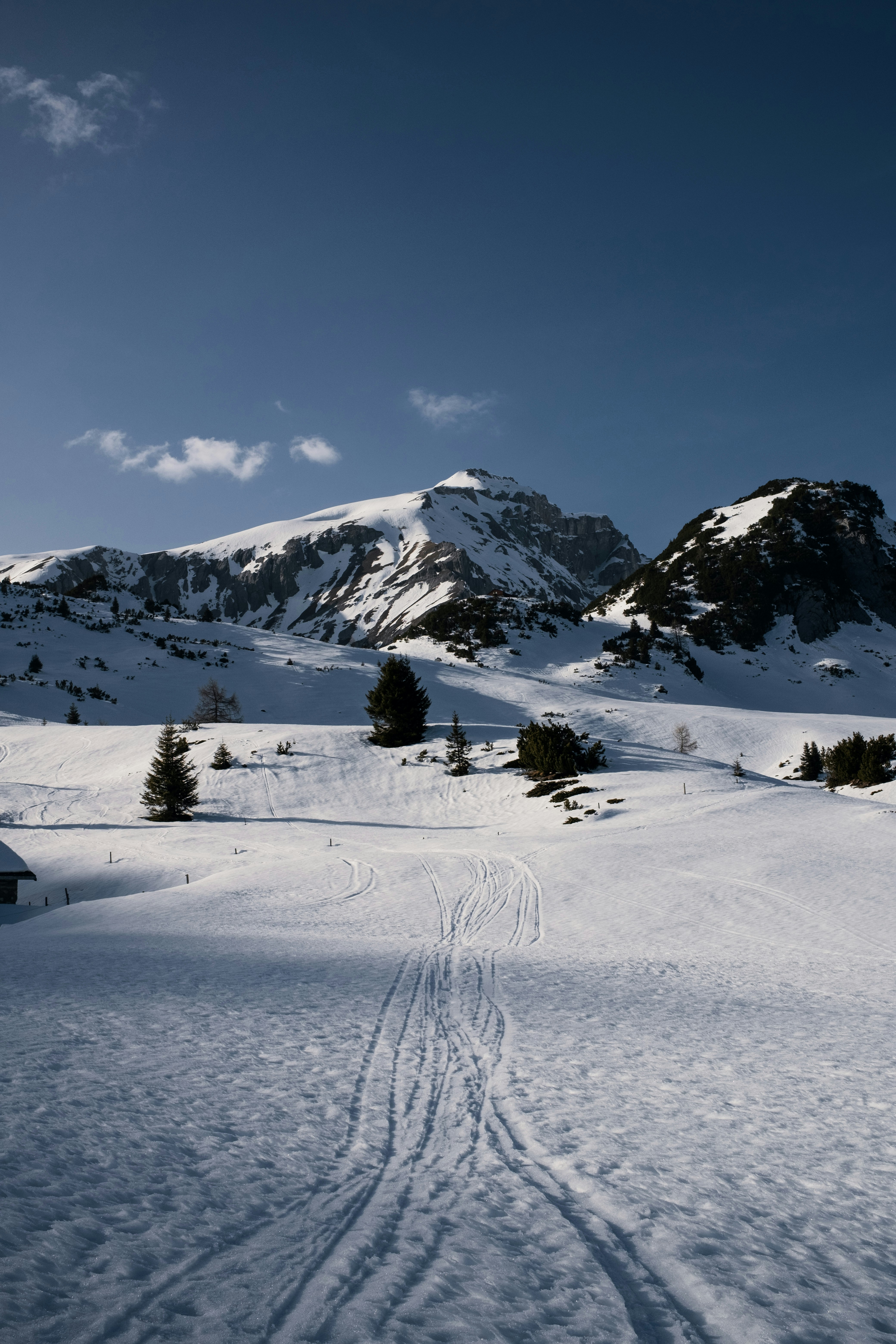 Snowy mountain landscape with ski tracks under blue sky