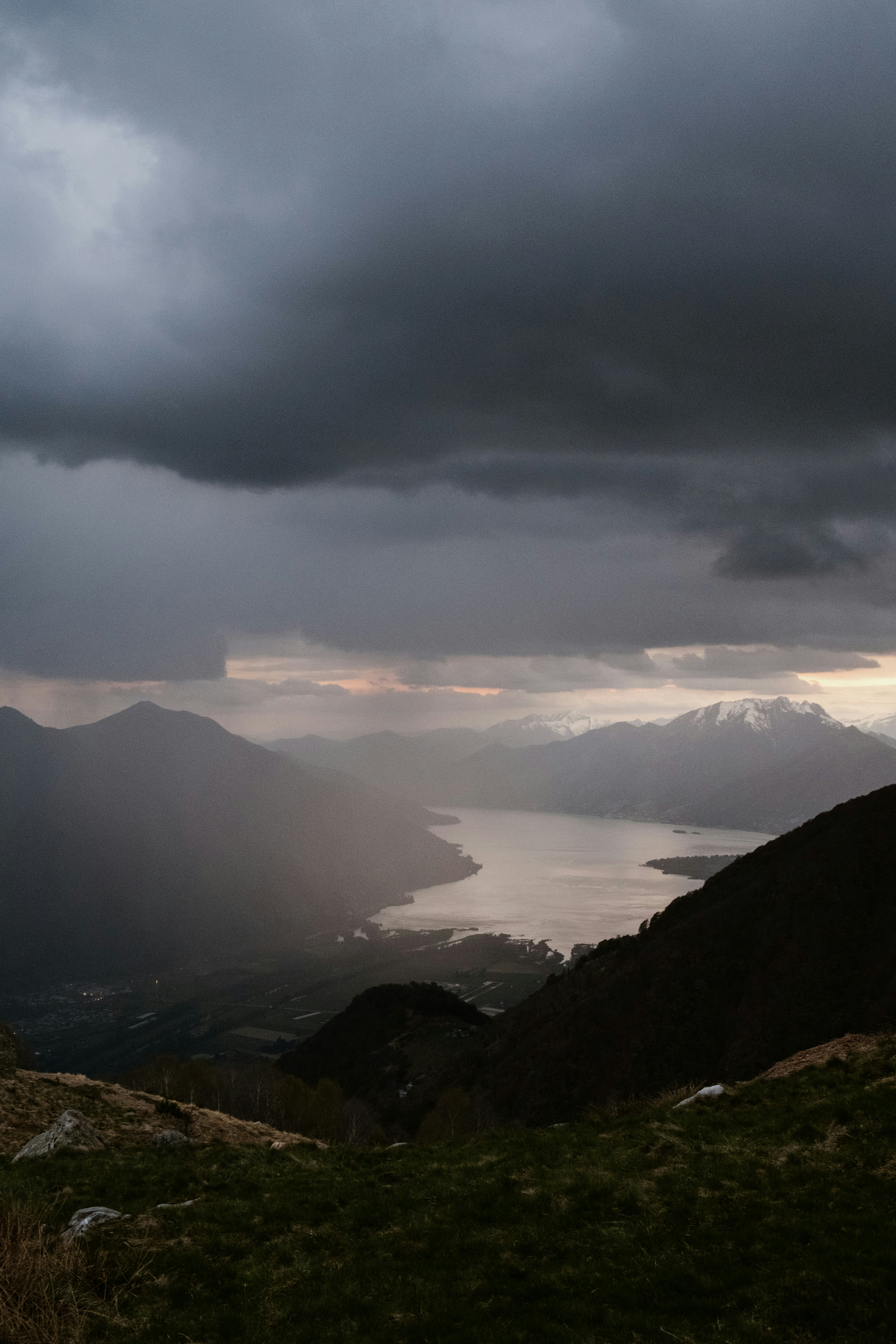 Dramatic storm clouds over a serene lake and mountains.