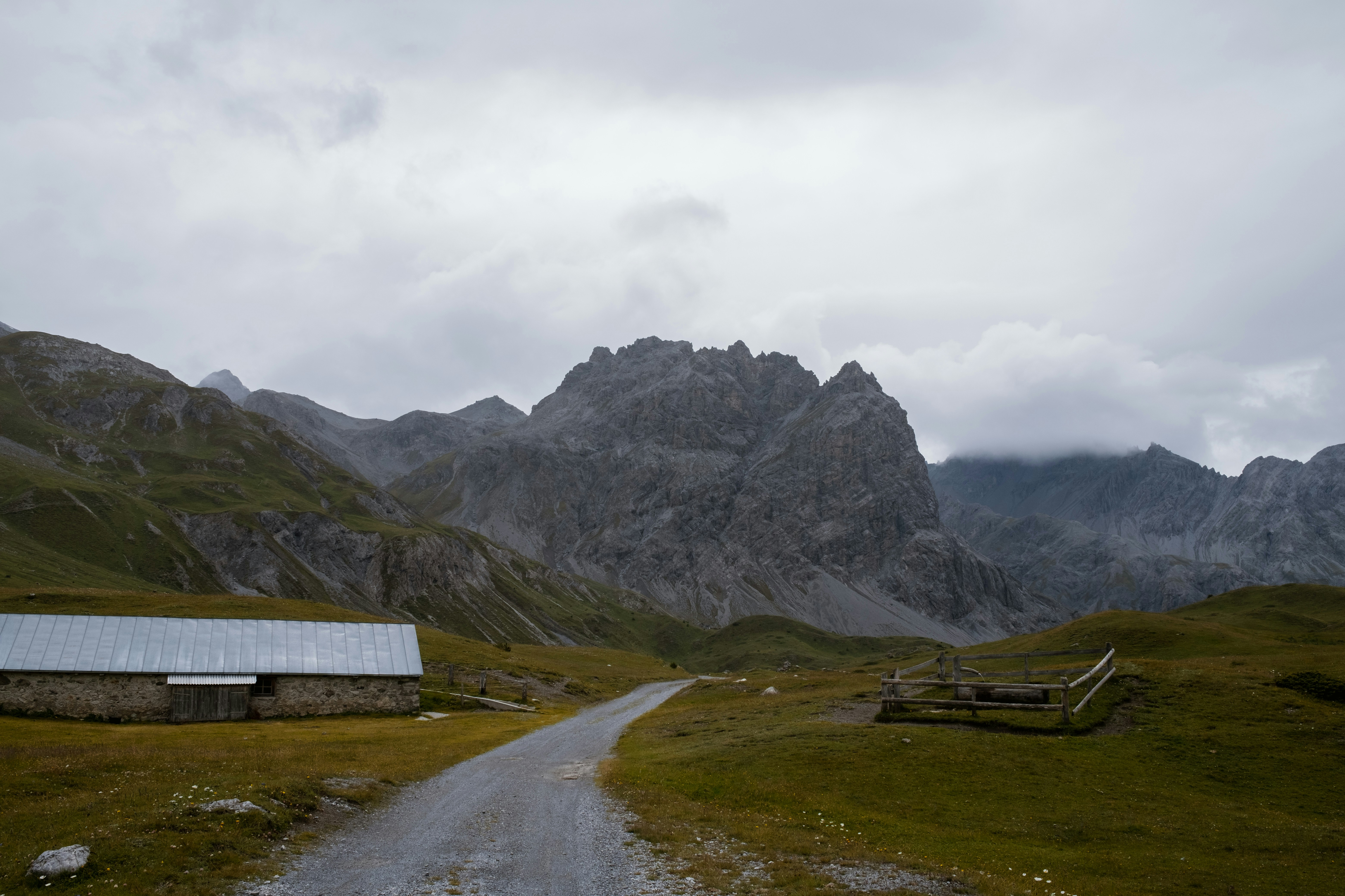 A dirt road leads to a barn in the mountains