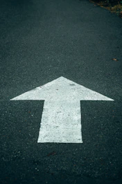 White arrow painted on dark asphalt road
