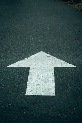 White arrow painted on dark asphalt road