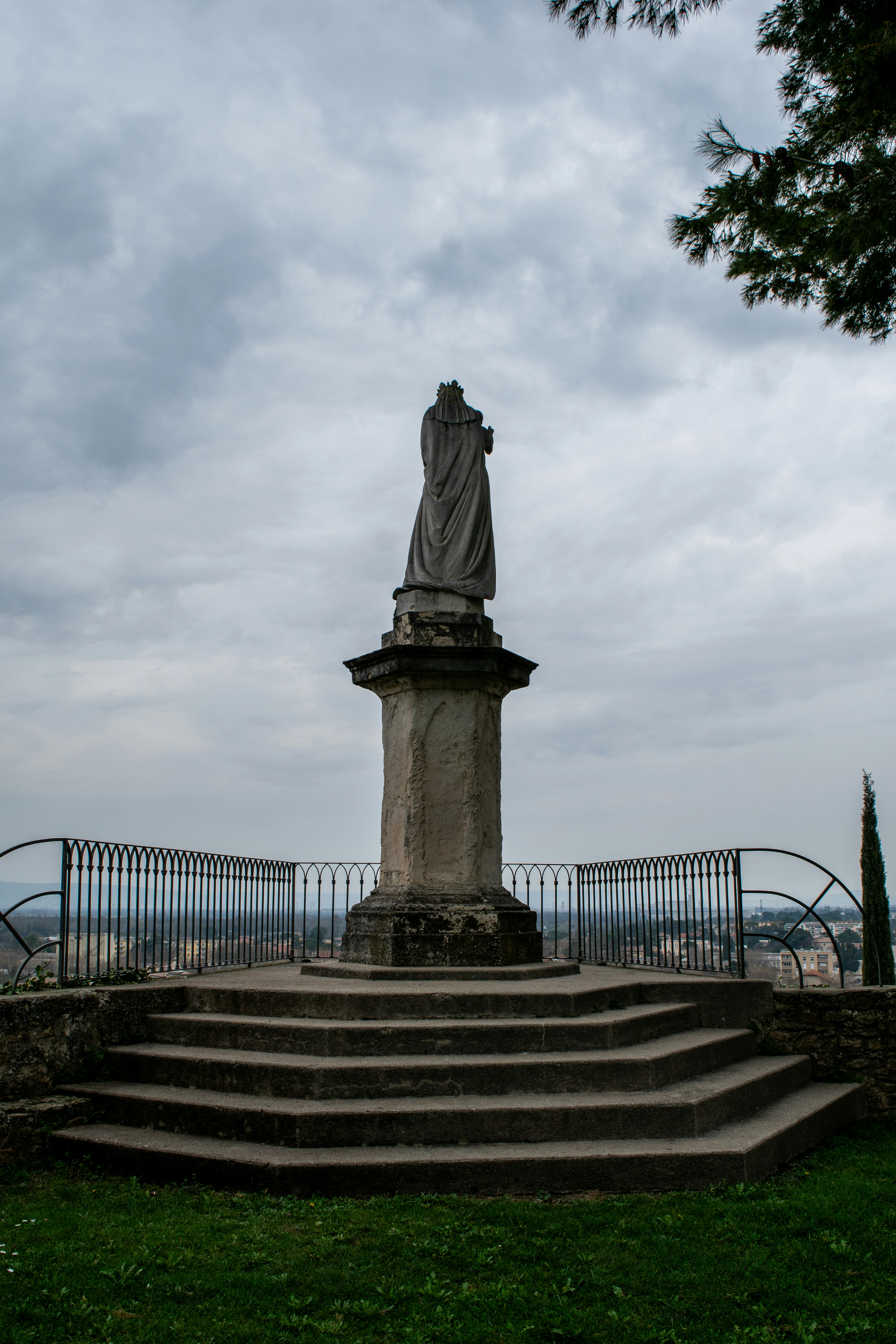 Stone statue on pedestal overlooking a city