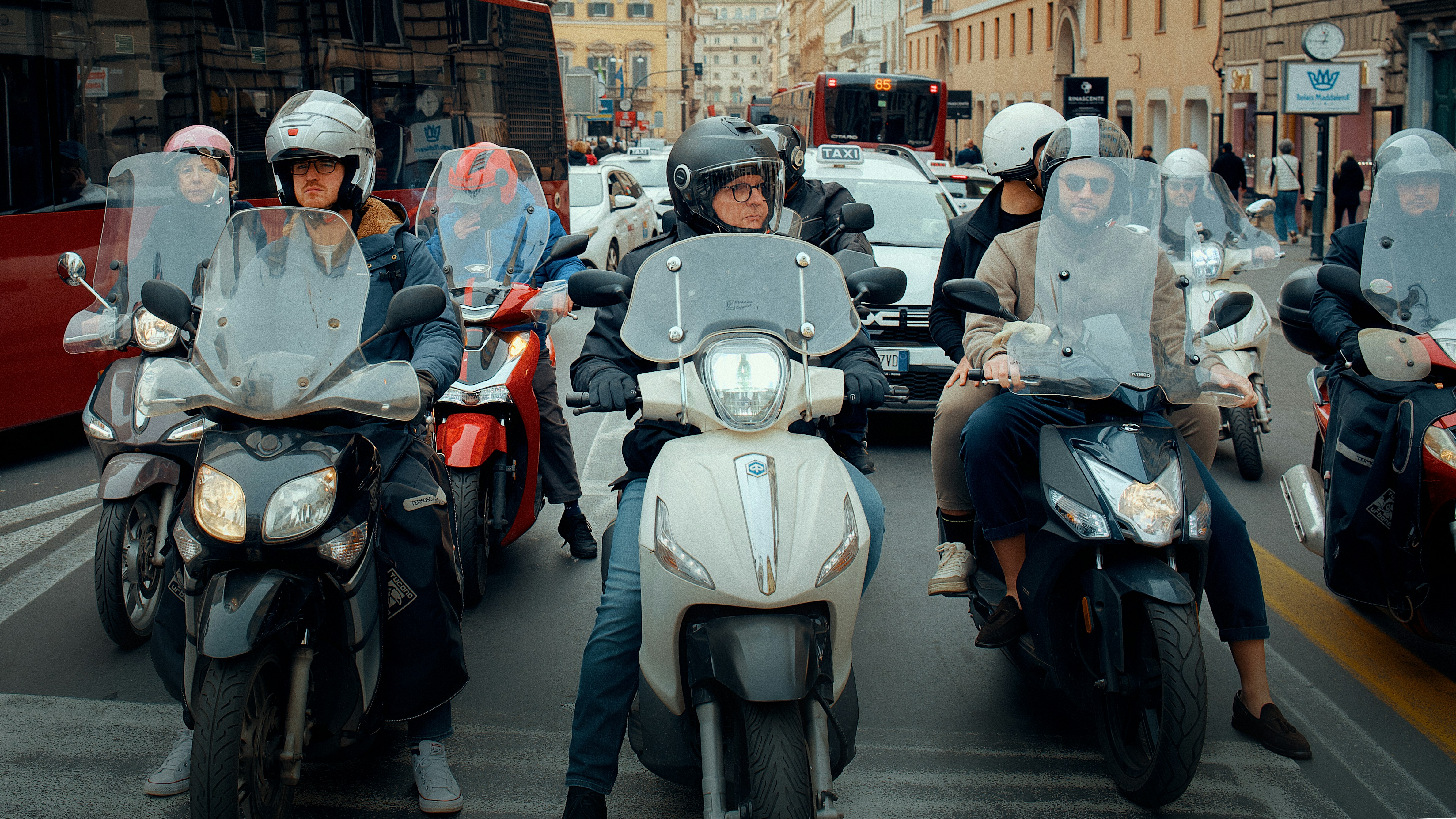 Group of people riding scooters on a city street.