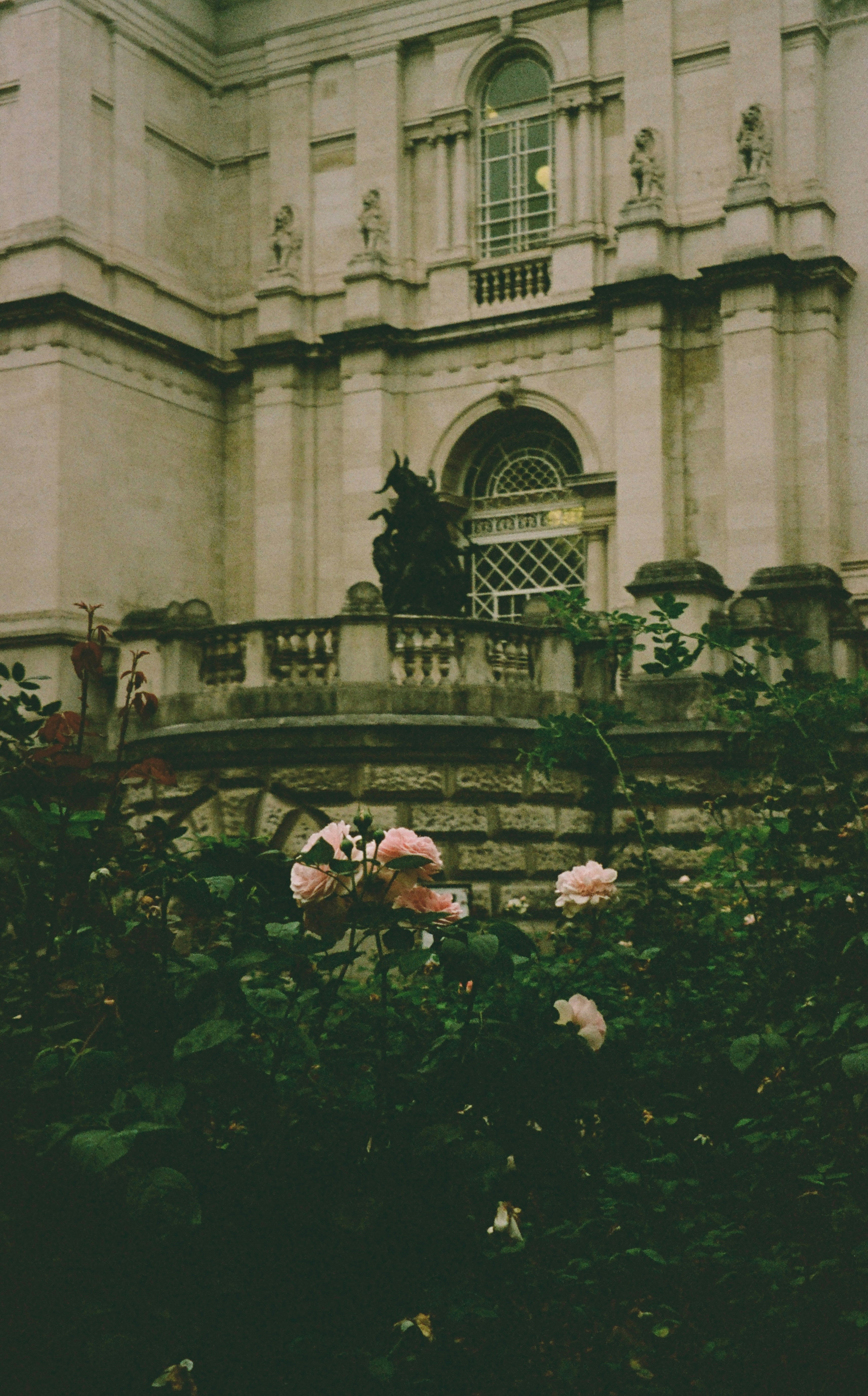 Edificio in pietra con finestre ornate e un giardino di rose.
